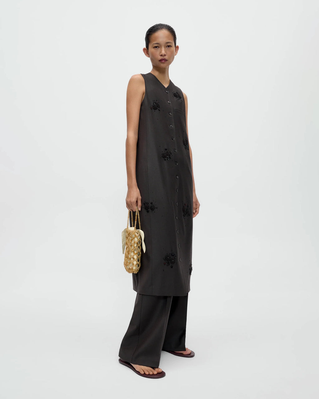 Model holding CORDERA Handmade Beaded Bag Jaspe Miel with a bottle-shaped silhouette and brown Ojo de Tigre beading.