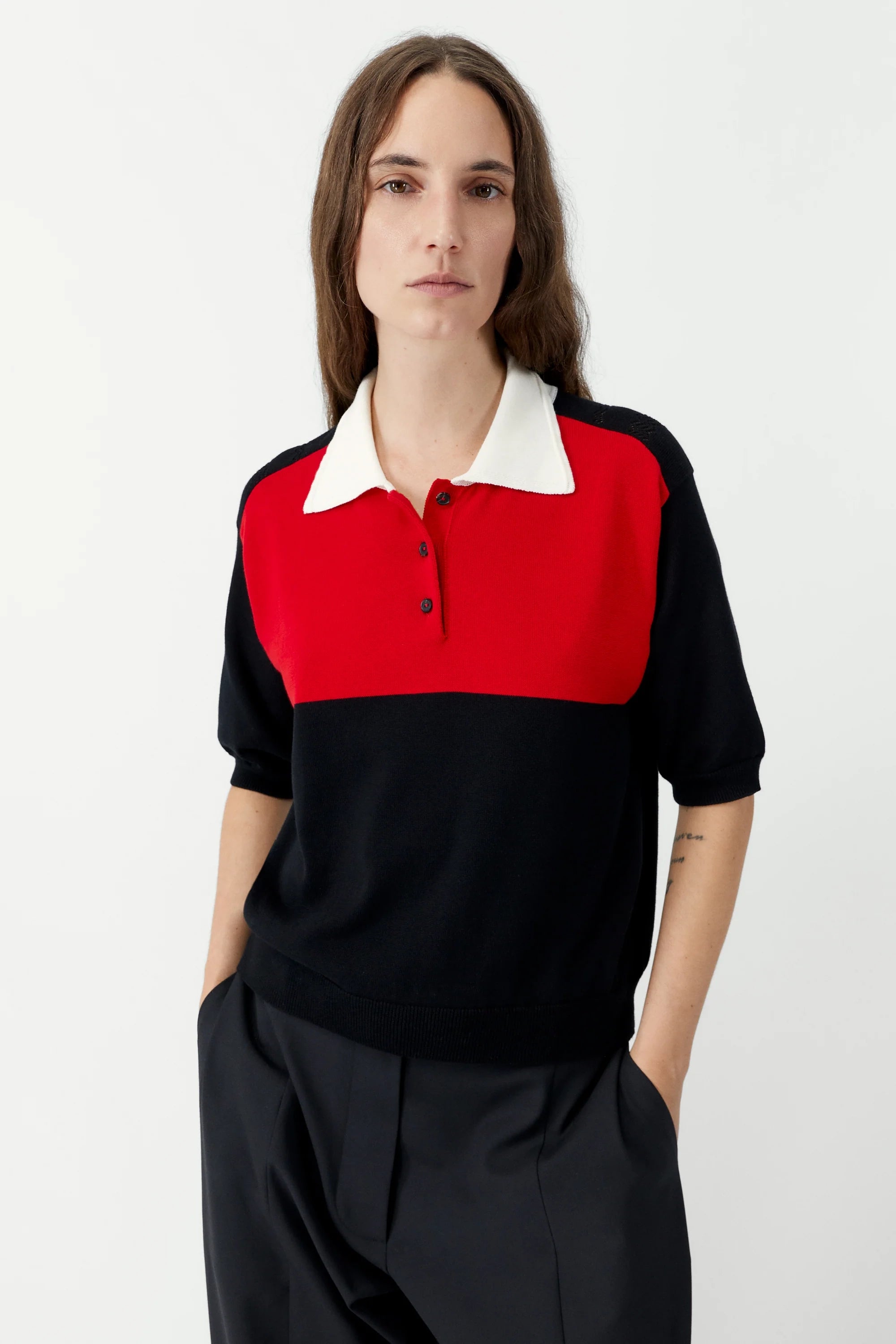 Person wearing a black, red, and white color-blocked shirt on a white background