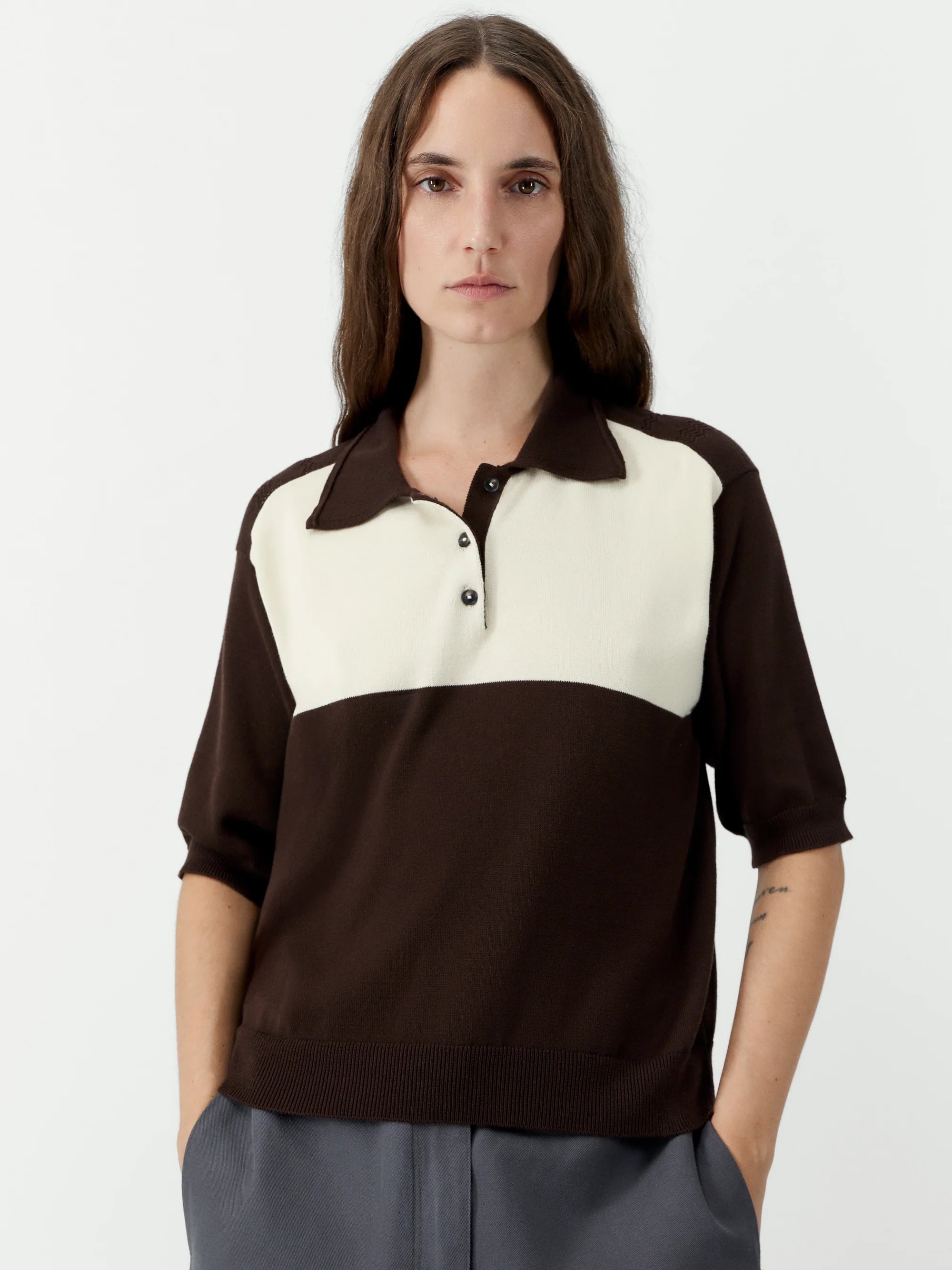 Woman wearing a brown and white polo shirt on a plain background