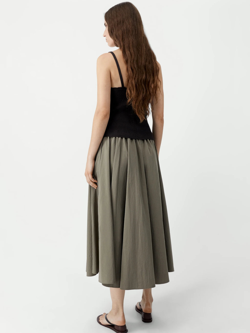 Woman wearing a black top and green skirt on a white background
