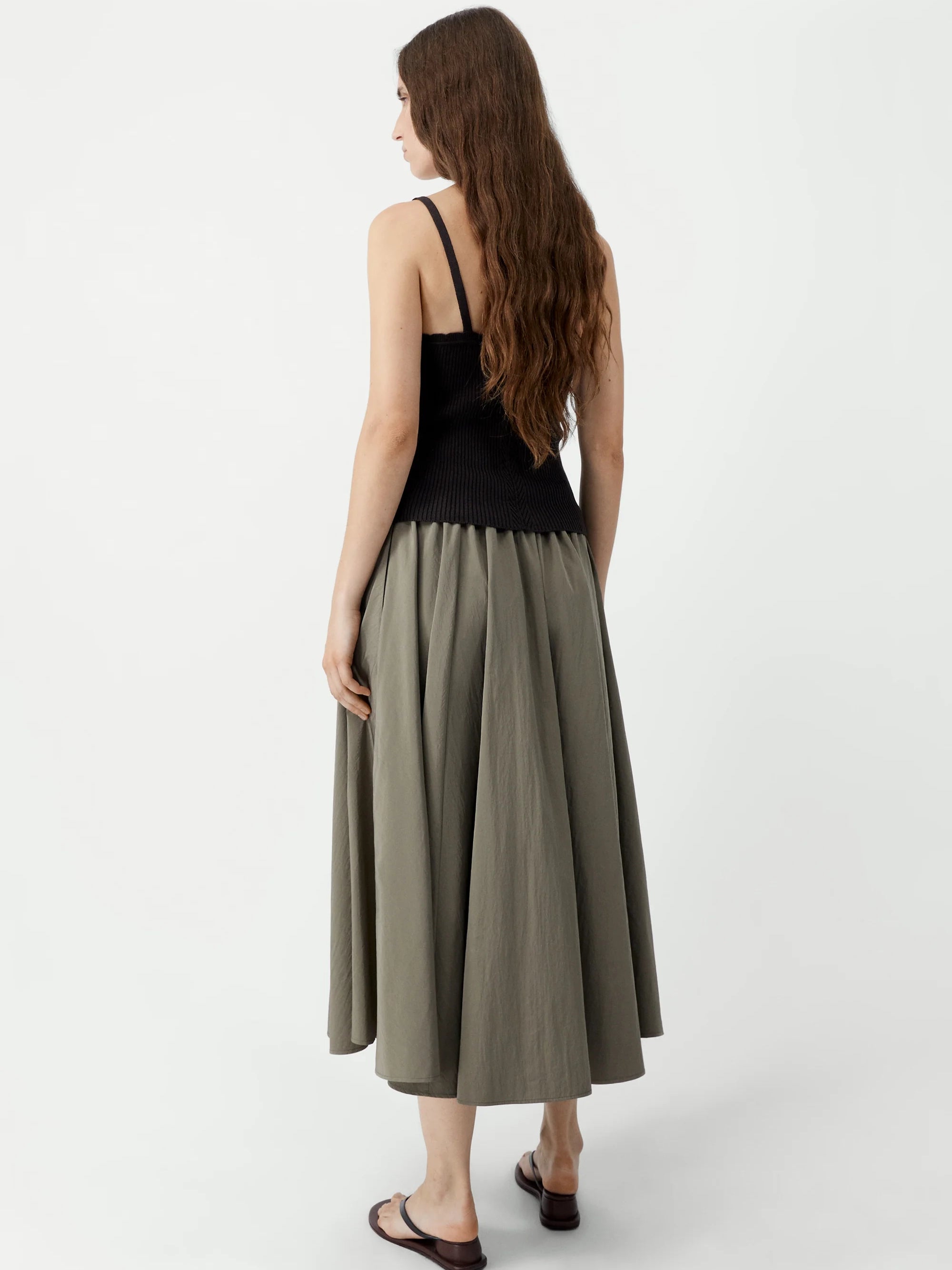 Woman wearing a black top and green skirt on a white background