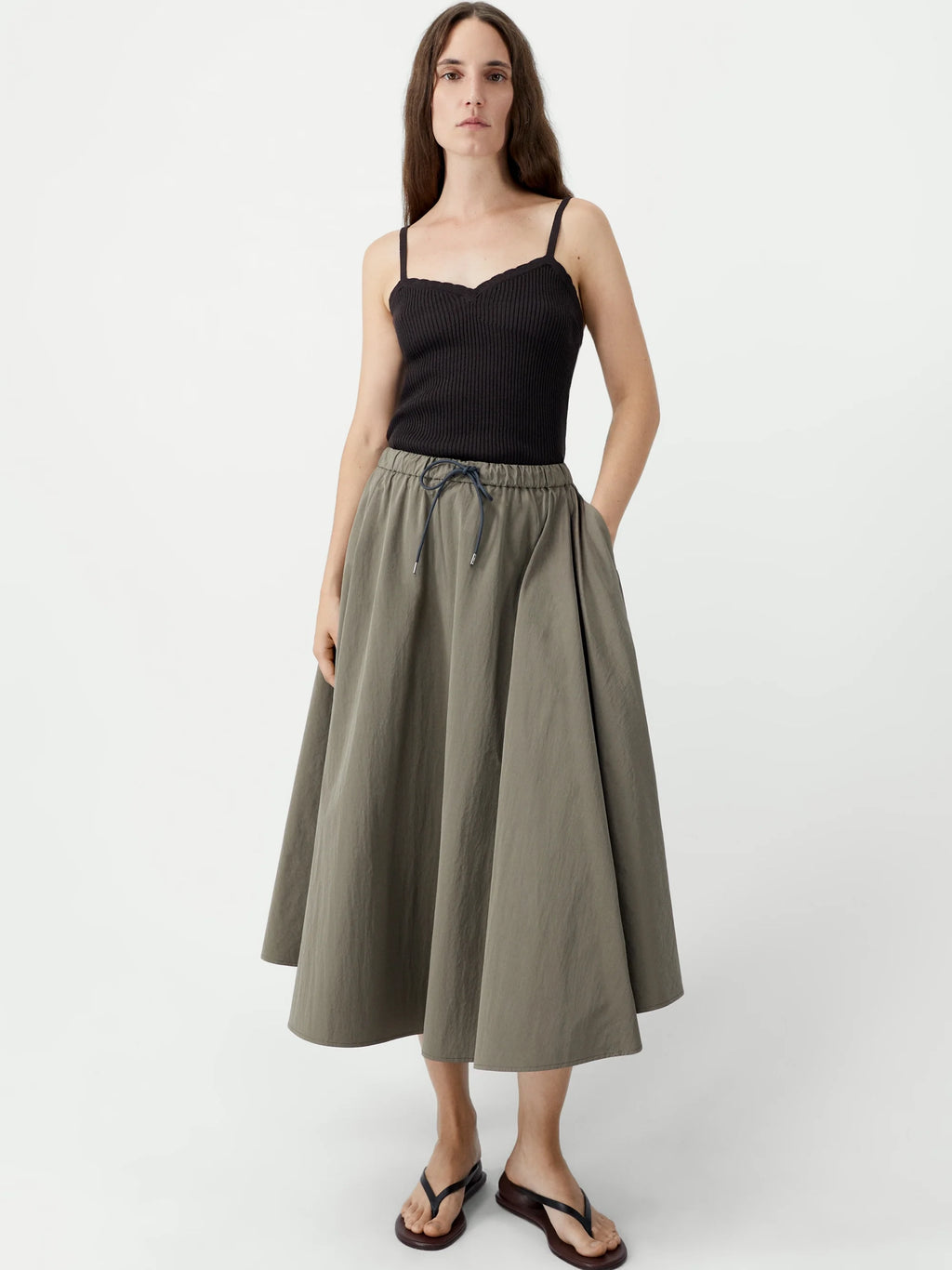 Woman wearing a black top and green skirt on a white background