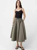 Woman wearing a black top and green skirt on a white background