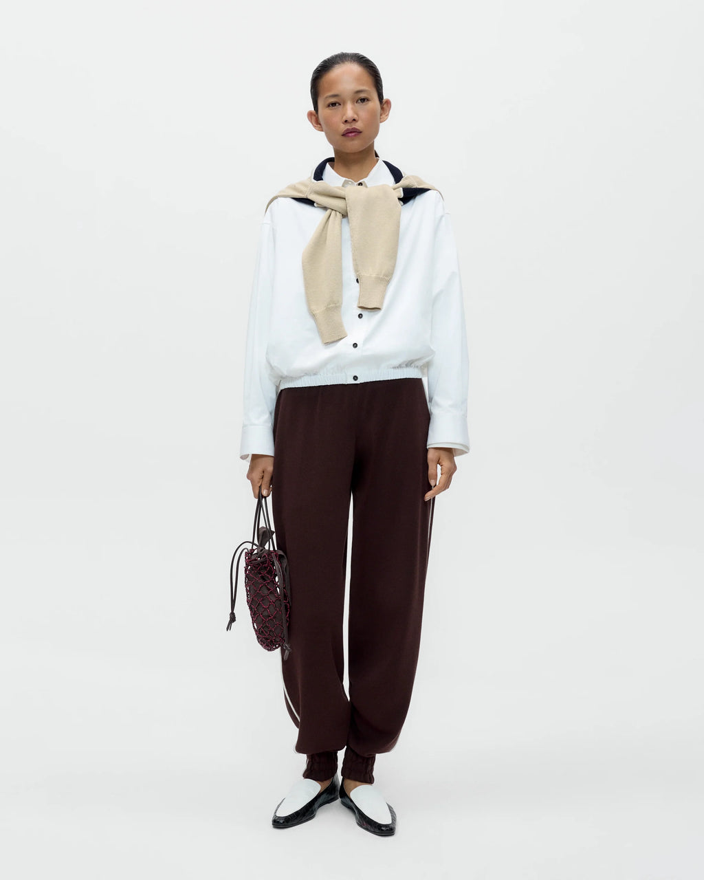 Model wearing CORDERA Organic Cotton Sporty Pants in brown with a contrasting white side stripe and gathered hems.