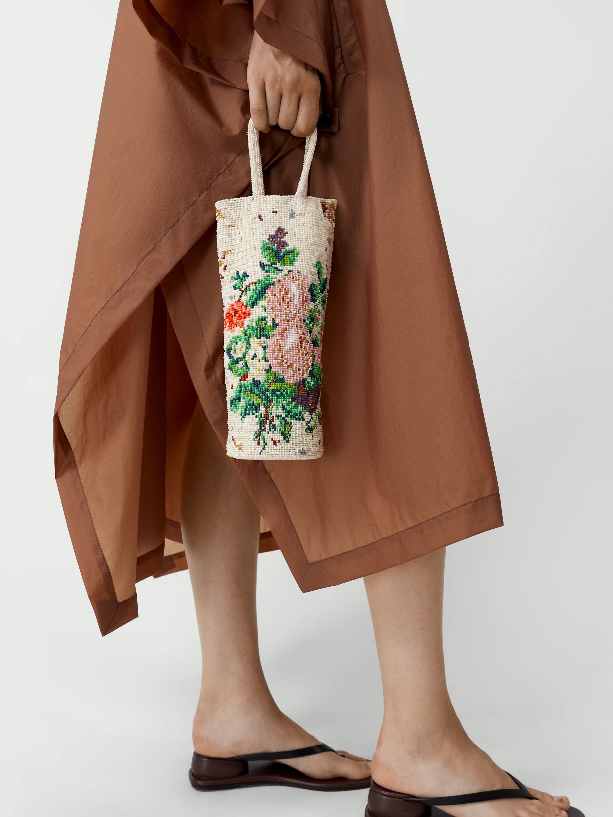 Person holding a floral embroidered bag with a plain background