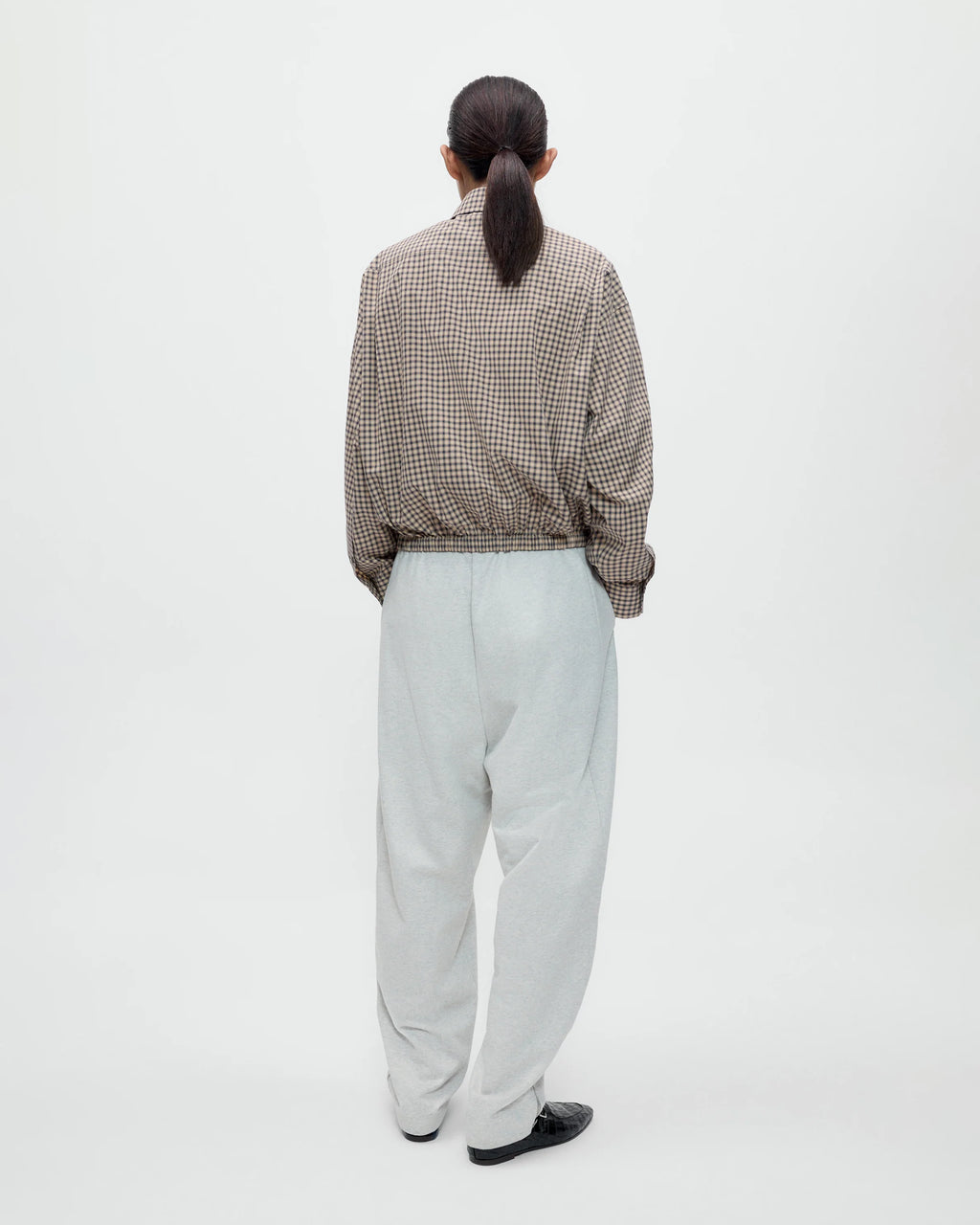 Model wearing CORDERA Lounge Pants in grey with a relaxed, straight silhouette and zippered hems.