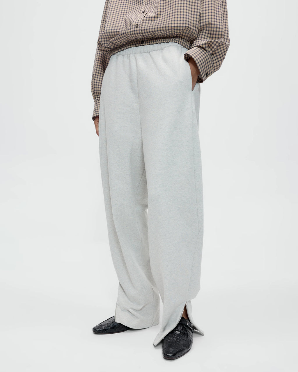 Model wearing CORDERA Lounge Pants in grey with a relaxed, straight silhouette and zippered hems.