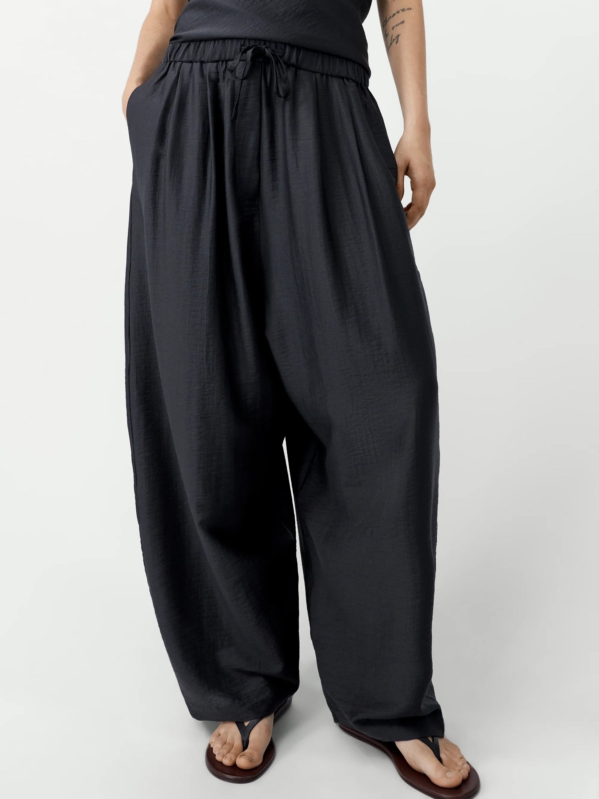 Person wearing black wide-leg pants on a white background