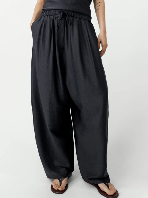 Person wearing black wide-leg pants on a white background