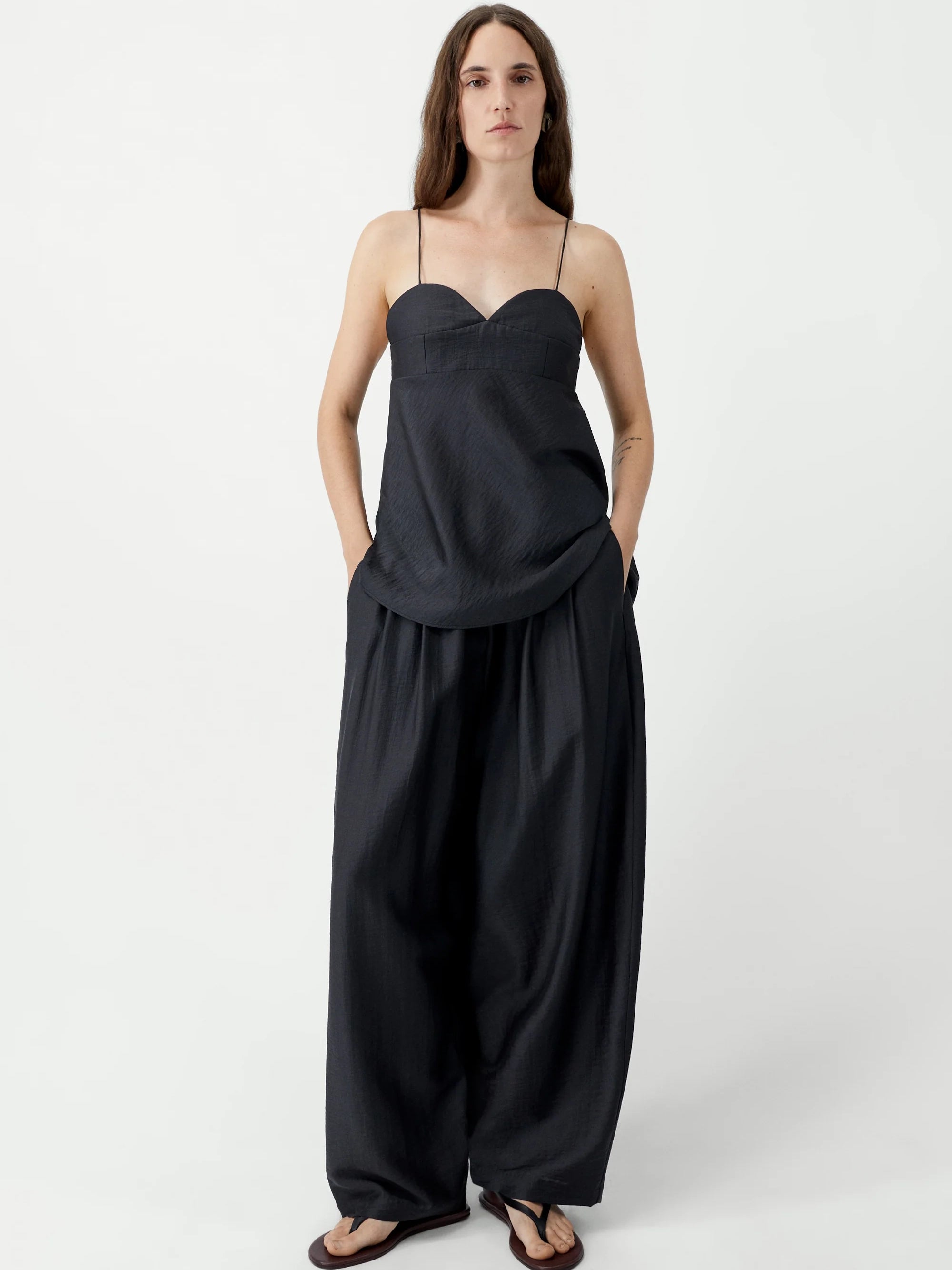Woman wearing a black strapless jumpsuit on a white background