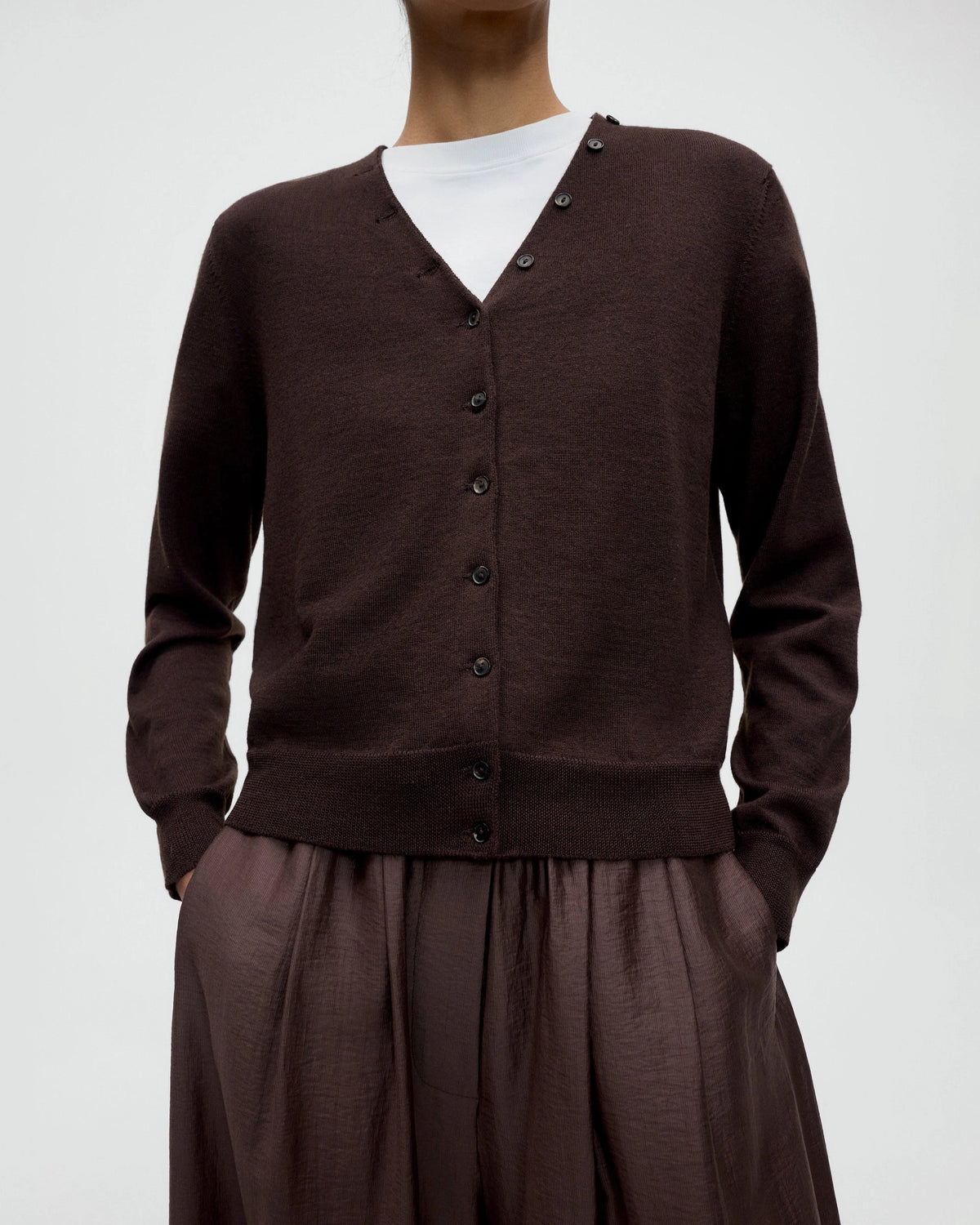 Model wearing CORDERA Merino Wool Button Cardigan in brown with a V-neckline and decorative buttons extending along the neckline.