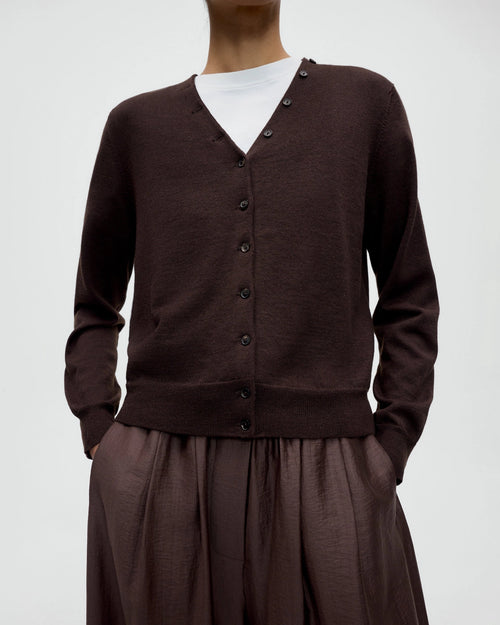 Model wearing CORDERA Merino Wool Button Cardigan in brown with a V-neckline and decorative buttons extending along the neckline.