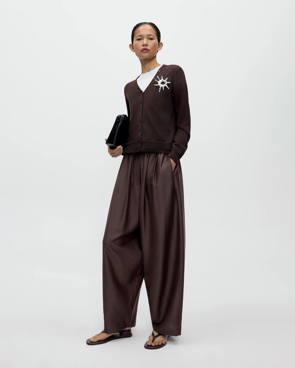 Model wearing CORDERA Merino Wool Button Cardigan in brown with a V-neckline and decorative buttons extending along the neckline.