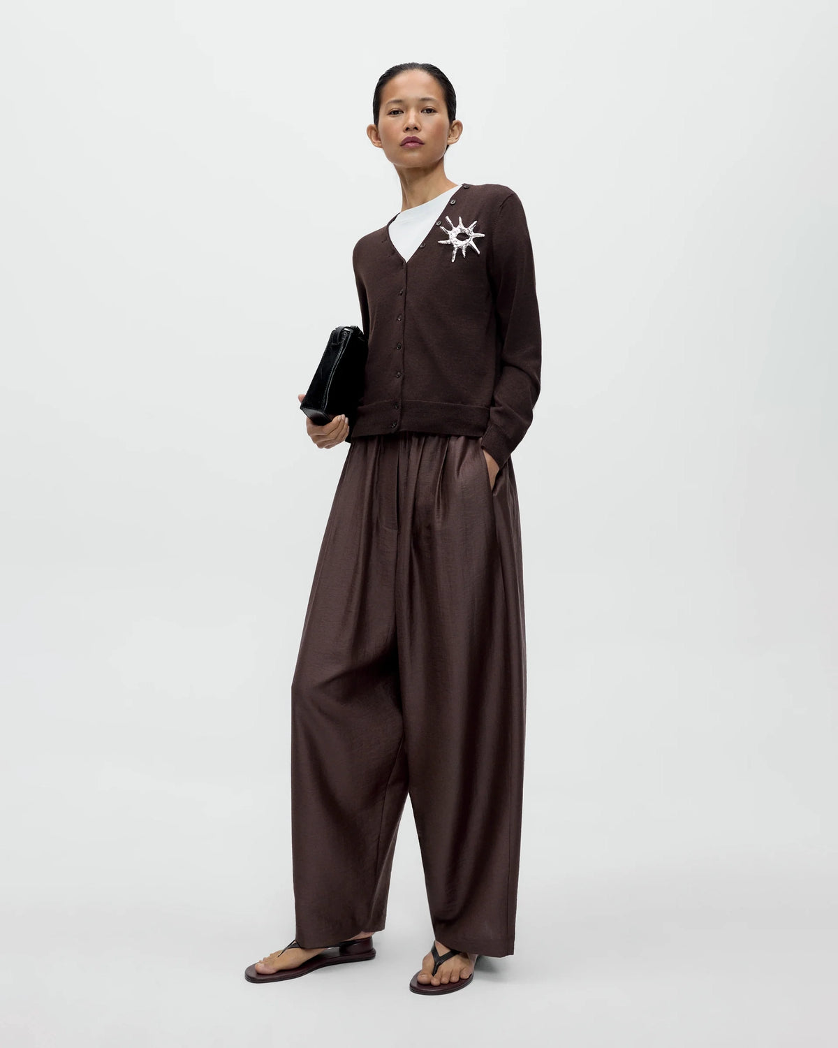 Model wearing CORDERA Merino Wool Button Cardigan in brown with a V-neckline and decorative buttons extending along the neckline.