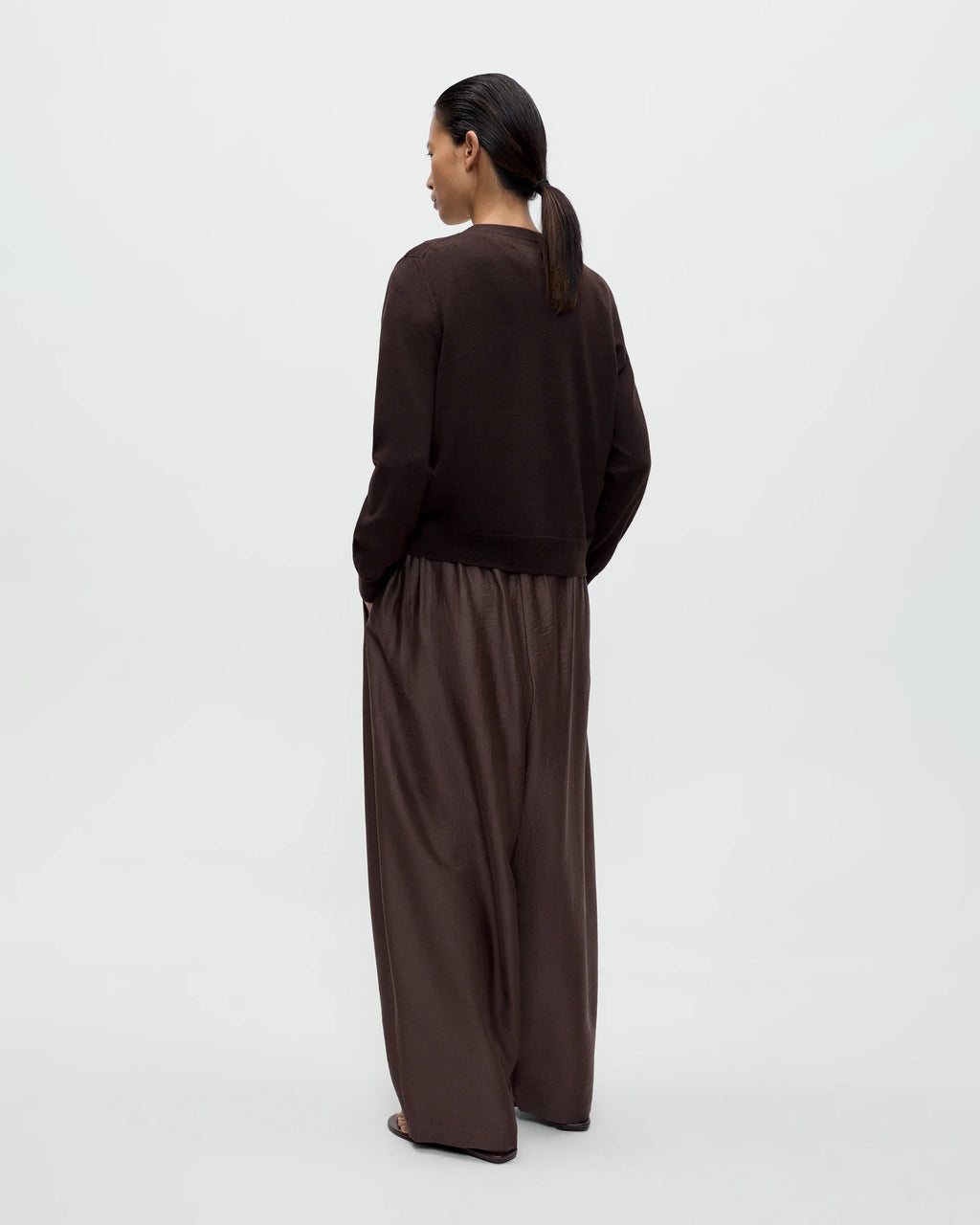 Model wearing CORDERA Merino Wool Button Cardigan in brown with a V-neckline and decorative buttons extending along the neckline.