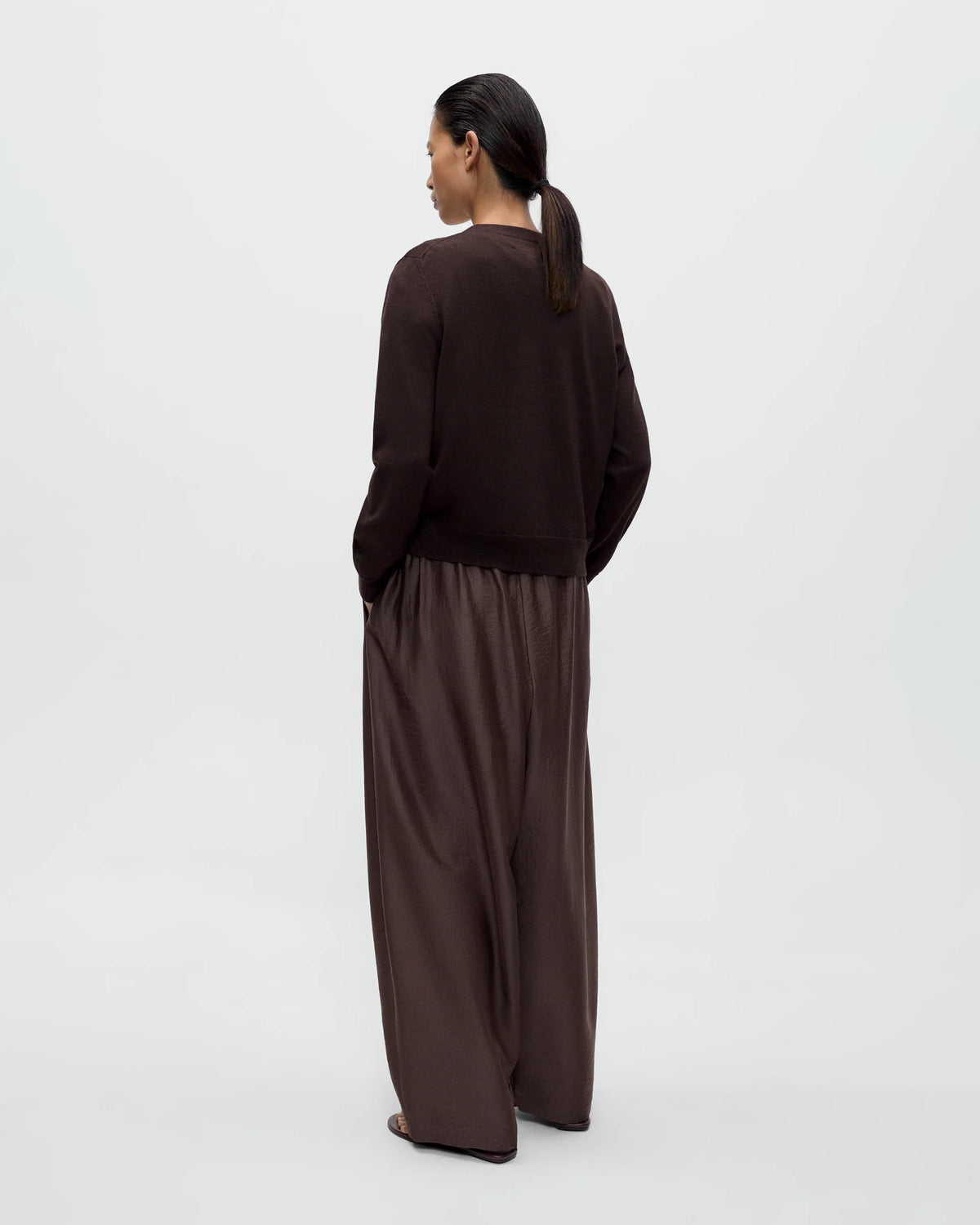 Model wearing CORDERA Merino Wool Button Cardigan in brown with a V-neckline and decorative buttons extending along the neckline.