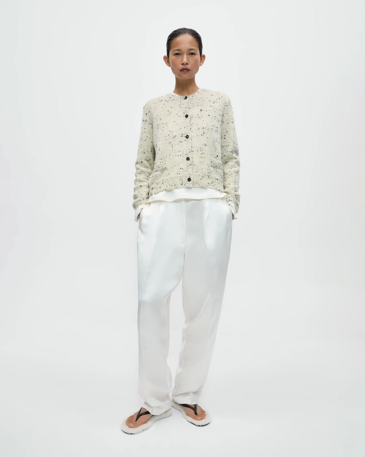 Model wearing CORDERA Merino Wool Flecked Cardigan in natural with a flecked chunky knit, button front and patch pockets.