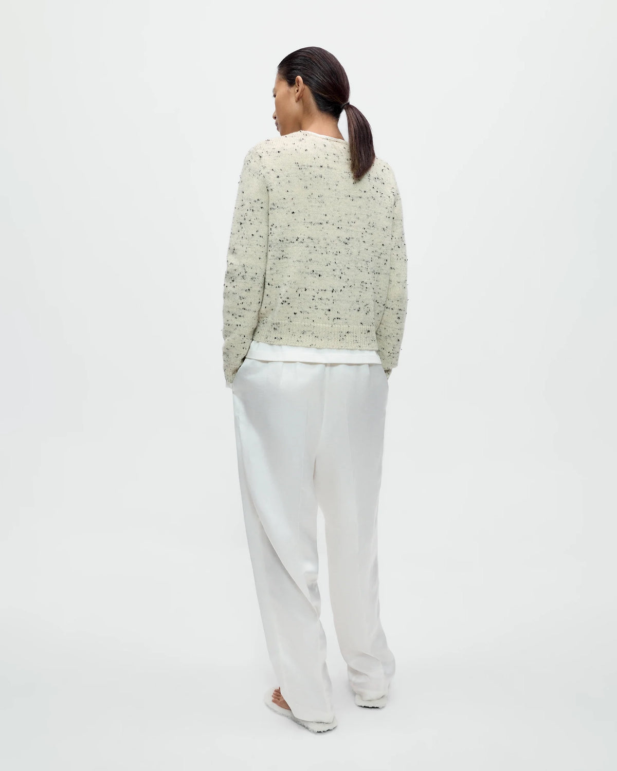 Model wearing CORDERA Merino Wool Flecked Cardigan in natural with a flecked chunky knit, button front and patch pockets.