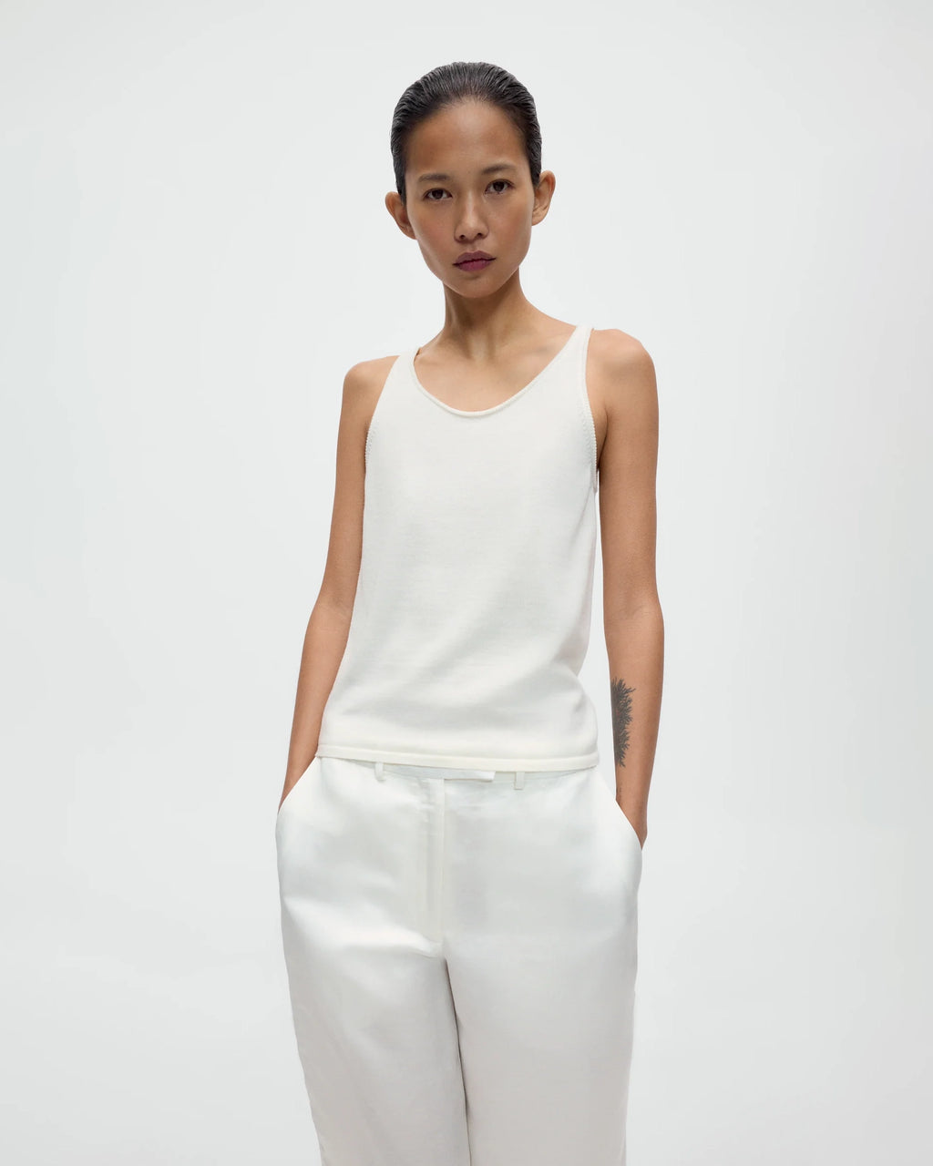 Model wearing CORDERA Merino Wool Tank Top in white with a fitted silhouette and oval neckline.