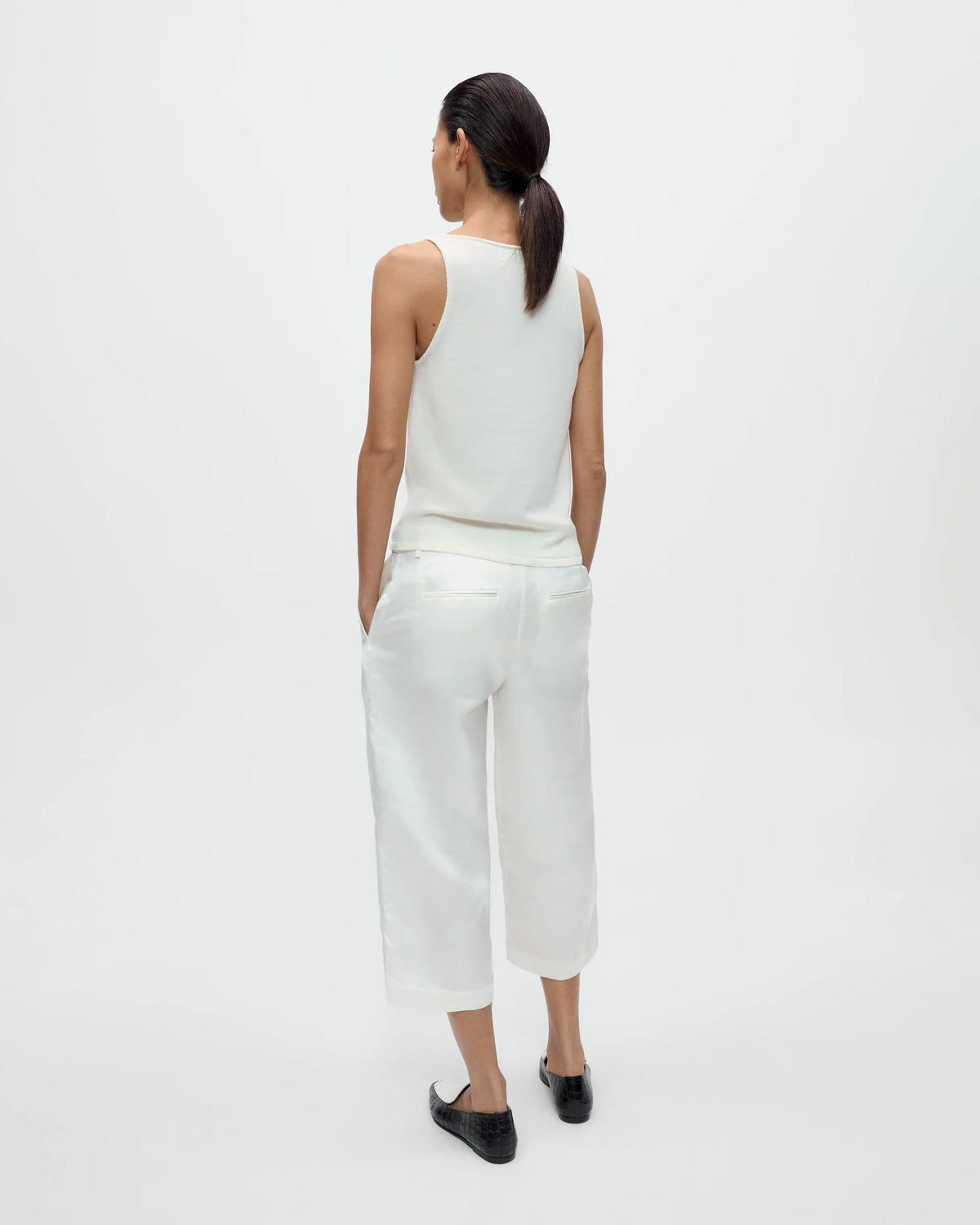 Model wearing CORDERA Merino Wool Tank Top in white with a fitted silhouette and oval neckline.