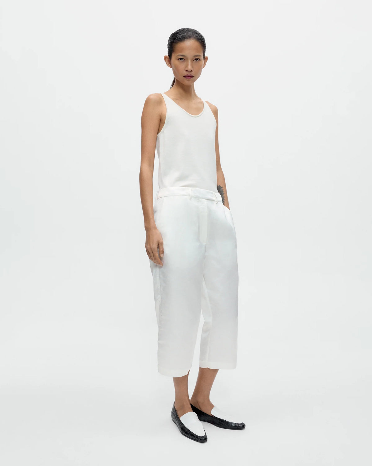 Model wearing CORDERA Merino Wool Tank Top in white with a fitted silhouette and oval neckline.
