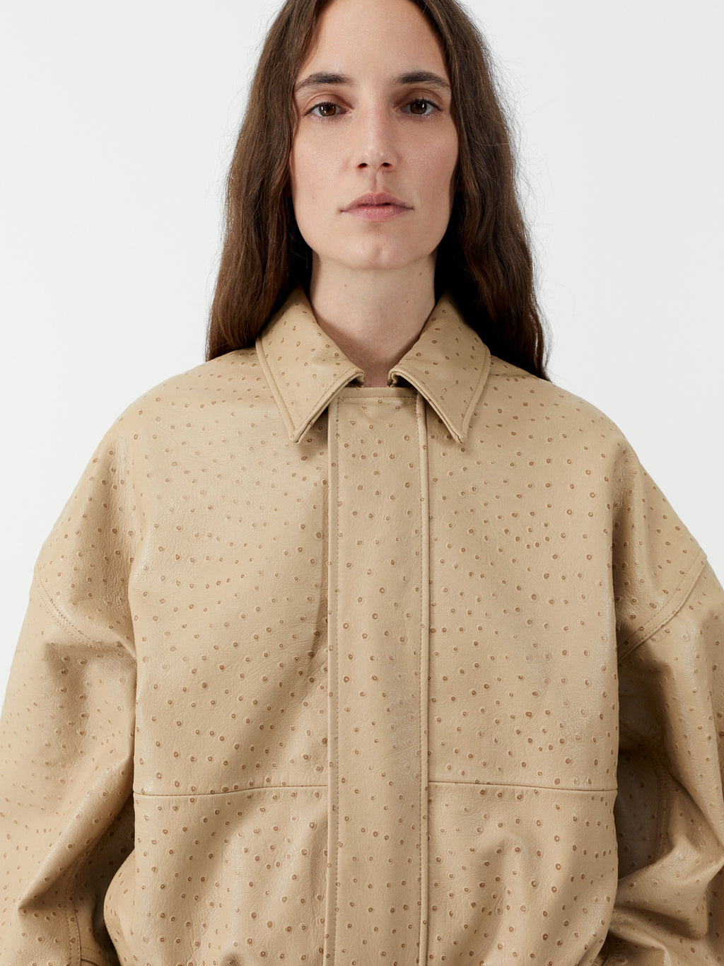 Person wearing a beige textured jacket on a white background