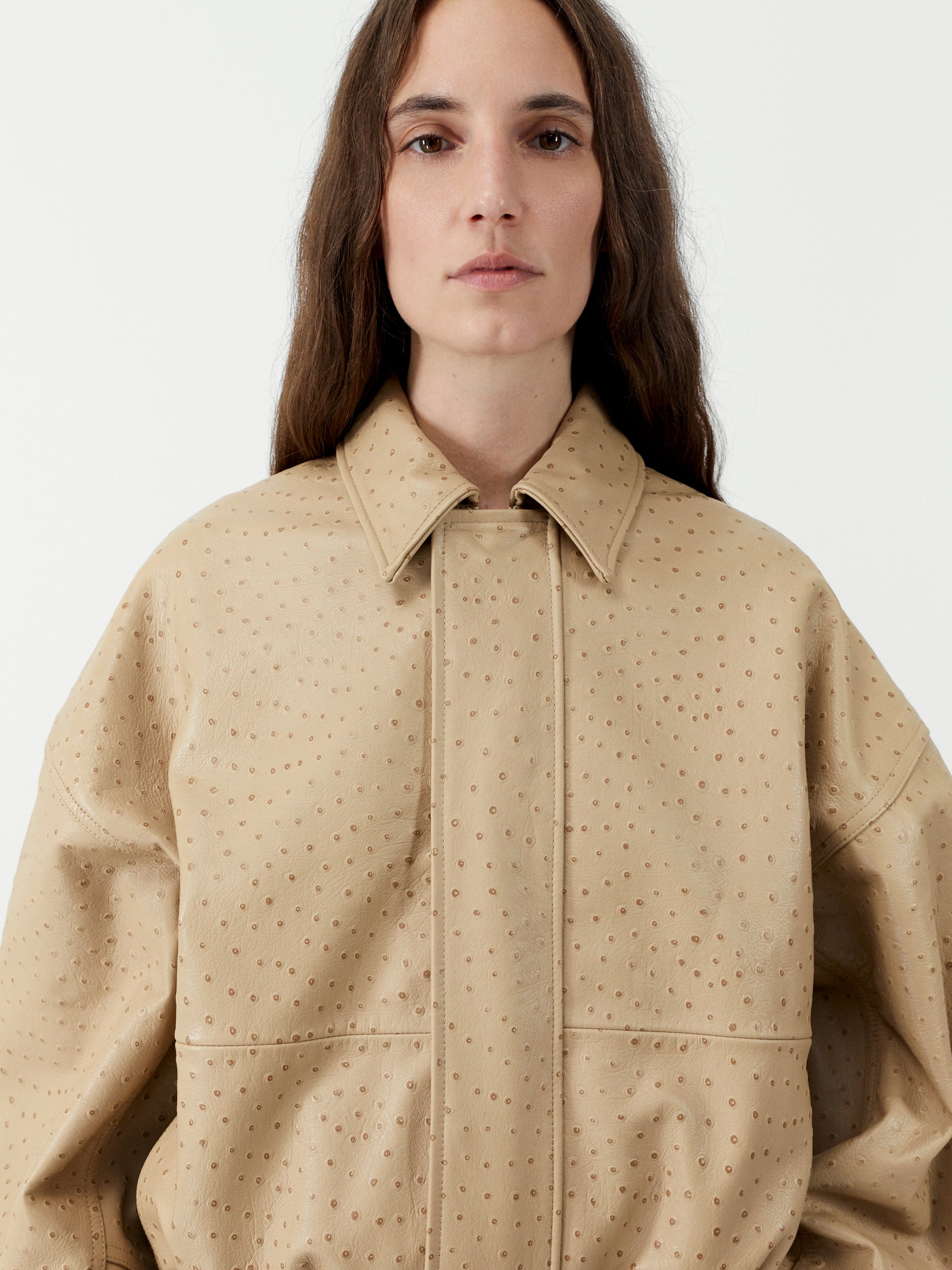 Person wearing a beige textured jacket on a white background
