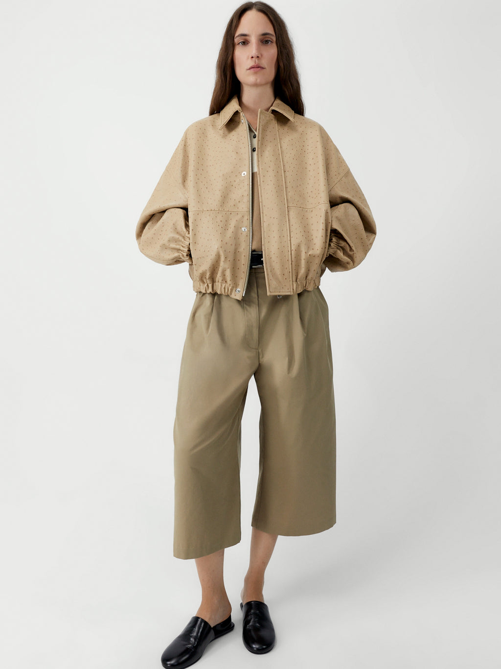 Person wearing a beige jacket and pants on a white background