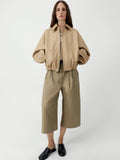 Person wearing a beige jacket and pants on a white background