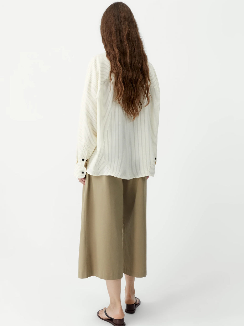 Person wearing a white sweater and beige pants on a white background