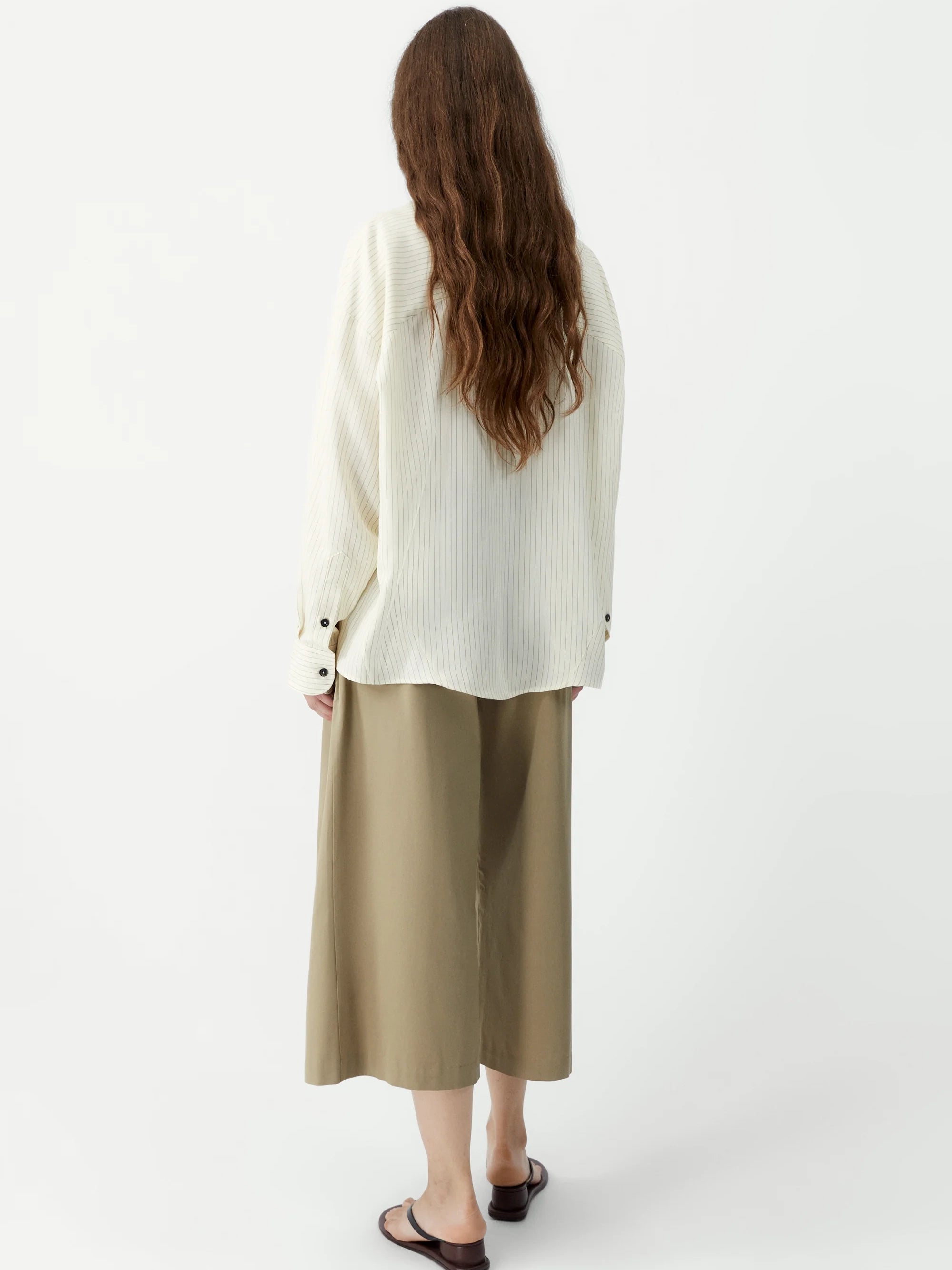Person wearing a white sweater and beige pants on a white background
