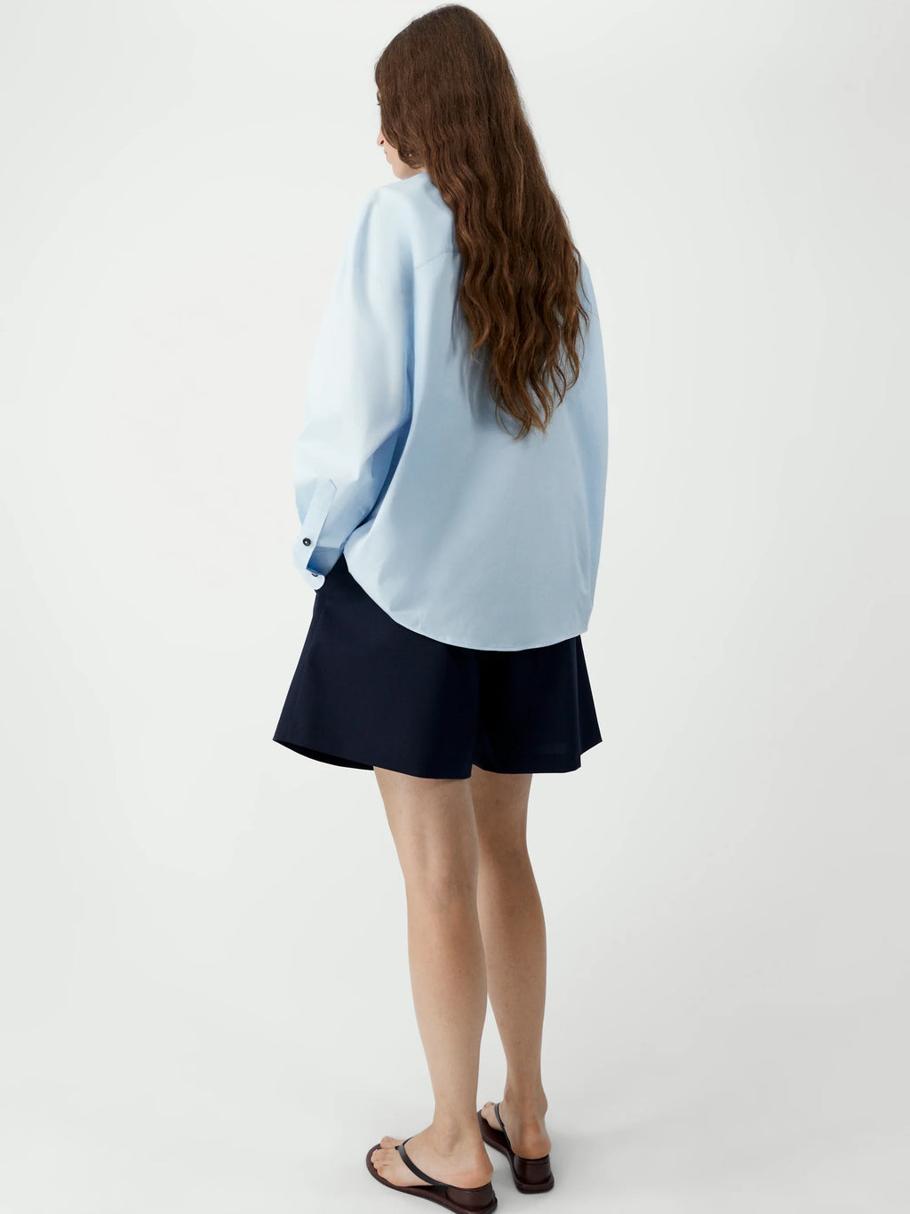 Person wearing a light blue cardigan over a black skirt on a white background