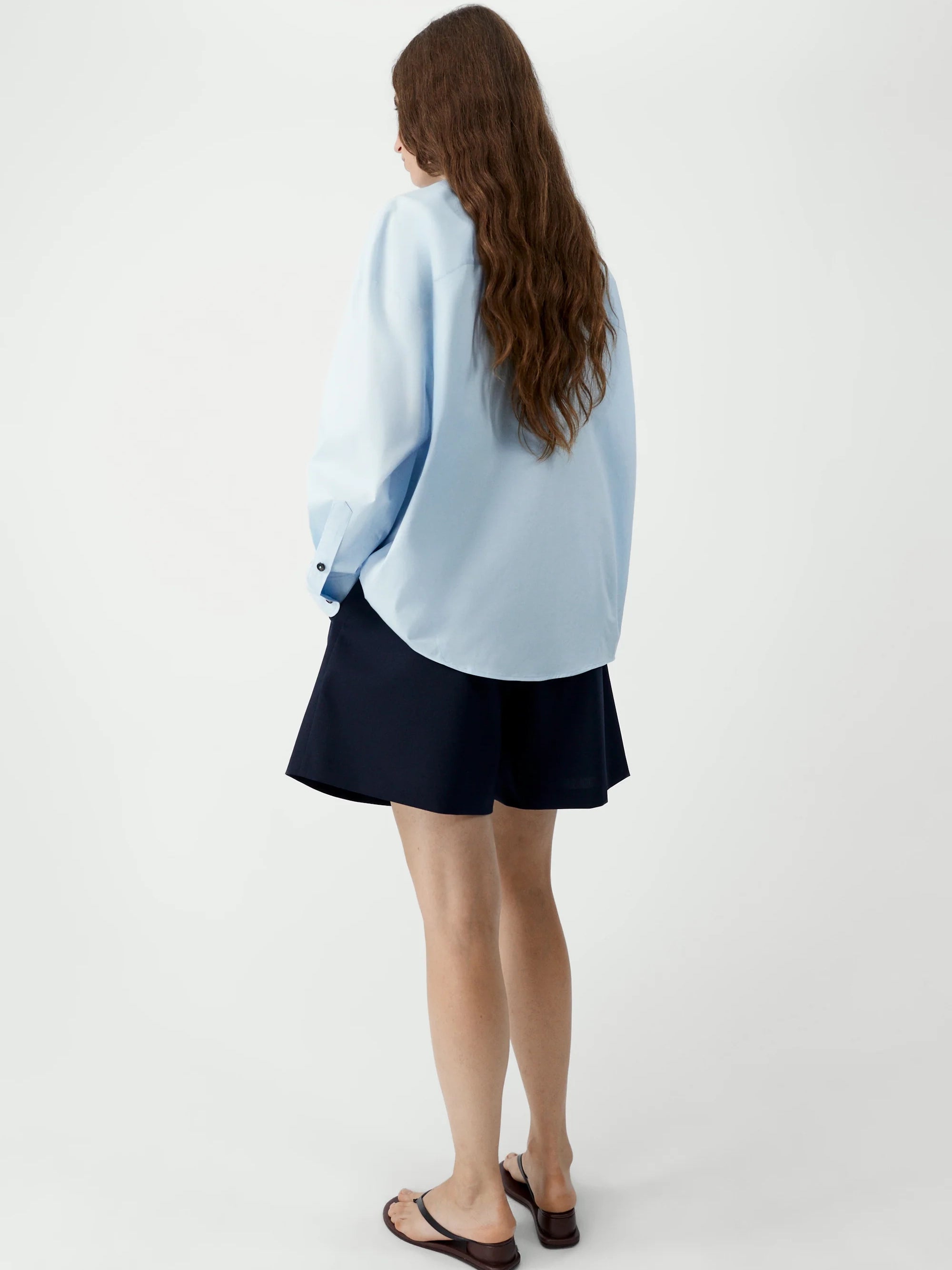 Person wearing a light blue cardigan over a black skirt on a white background