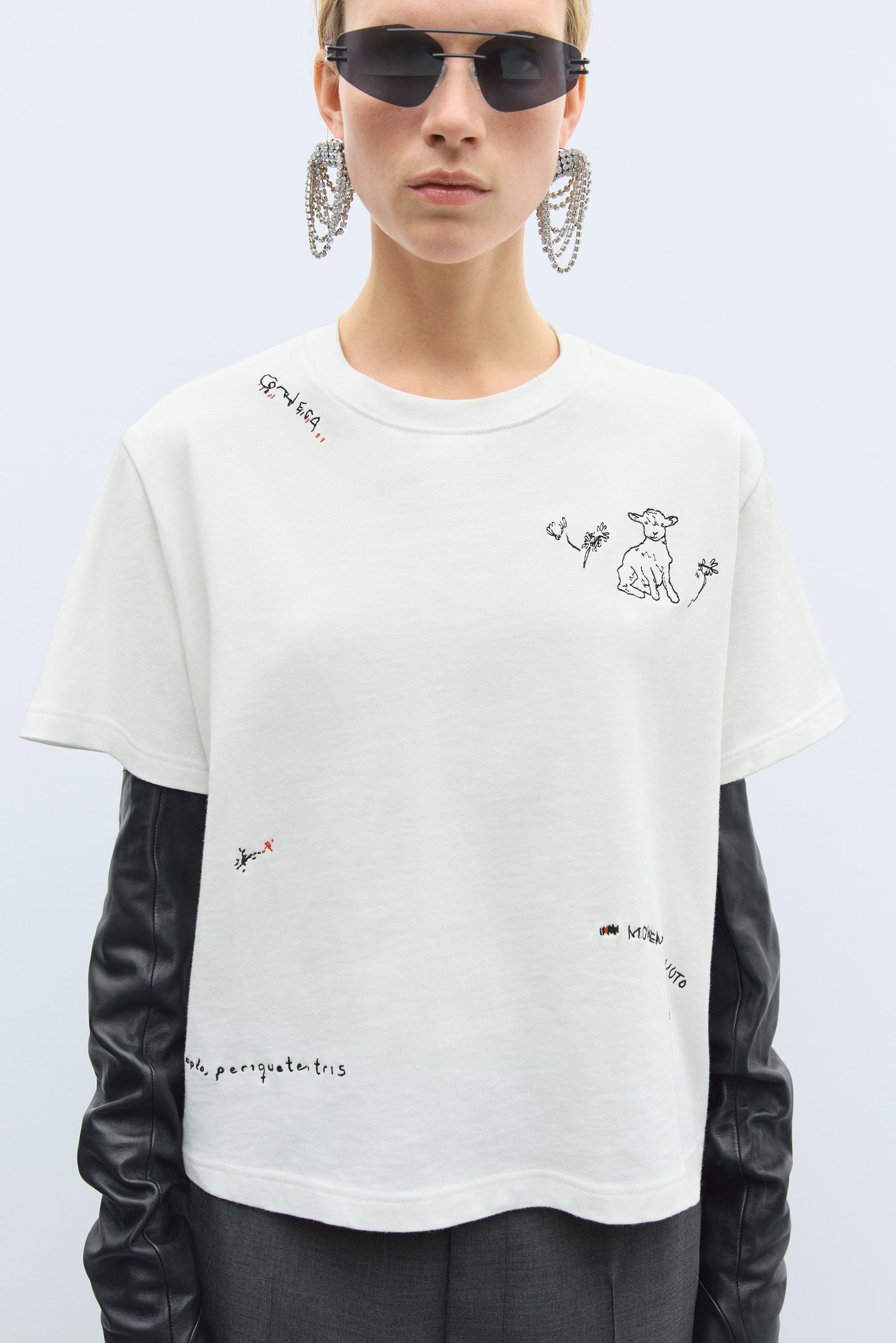 Person wearing a white t-shirt with black text and graphics on a light gray background
