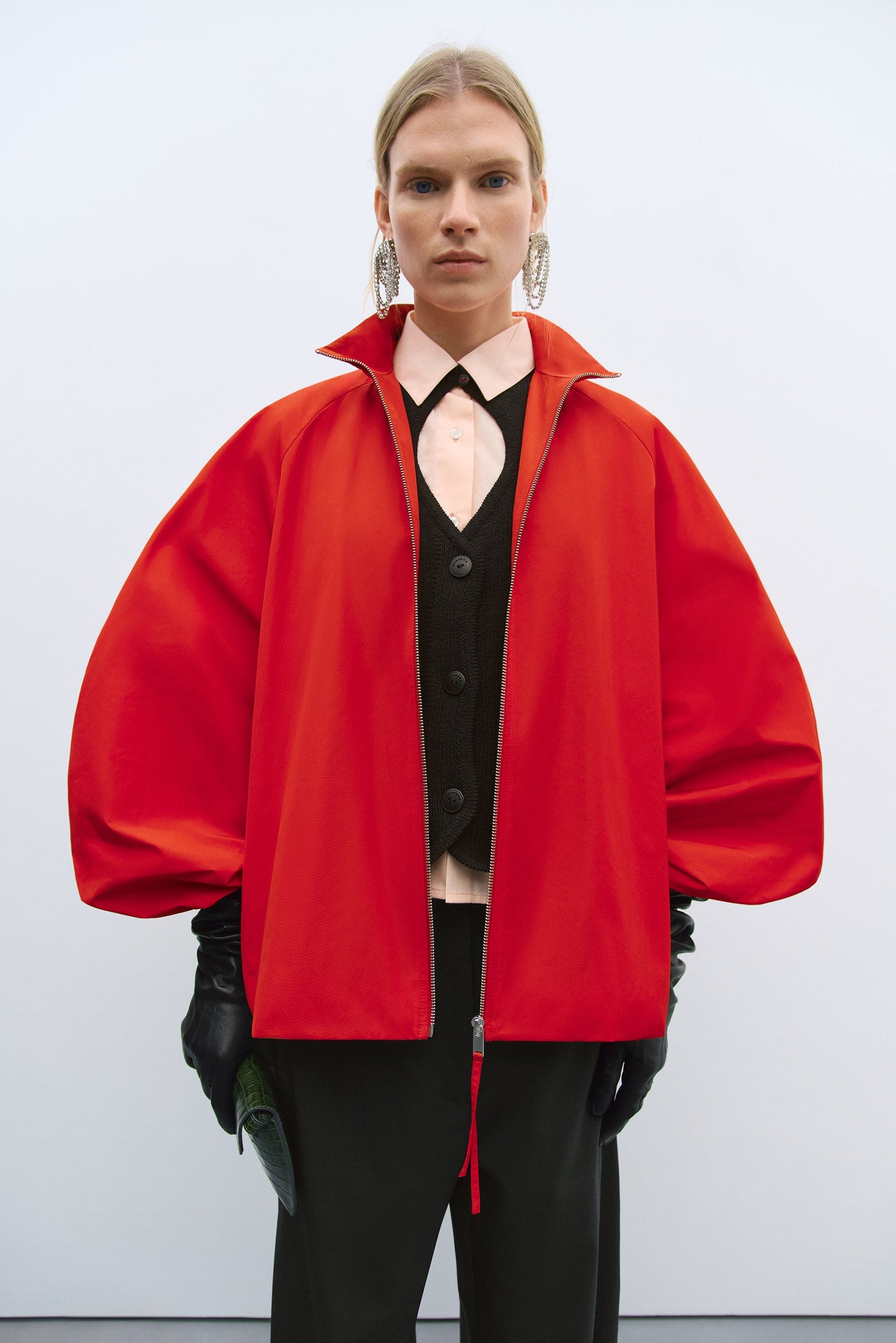 Person wearing a bright red coat over a black outfit on a white background