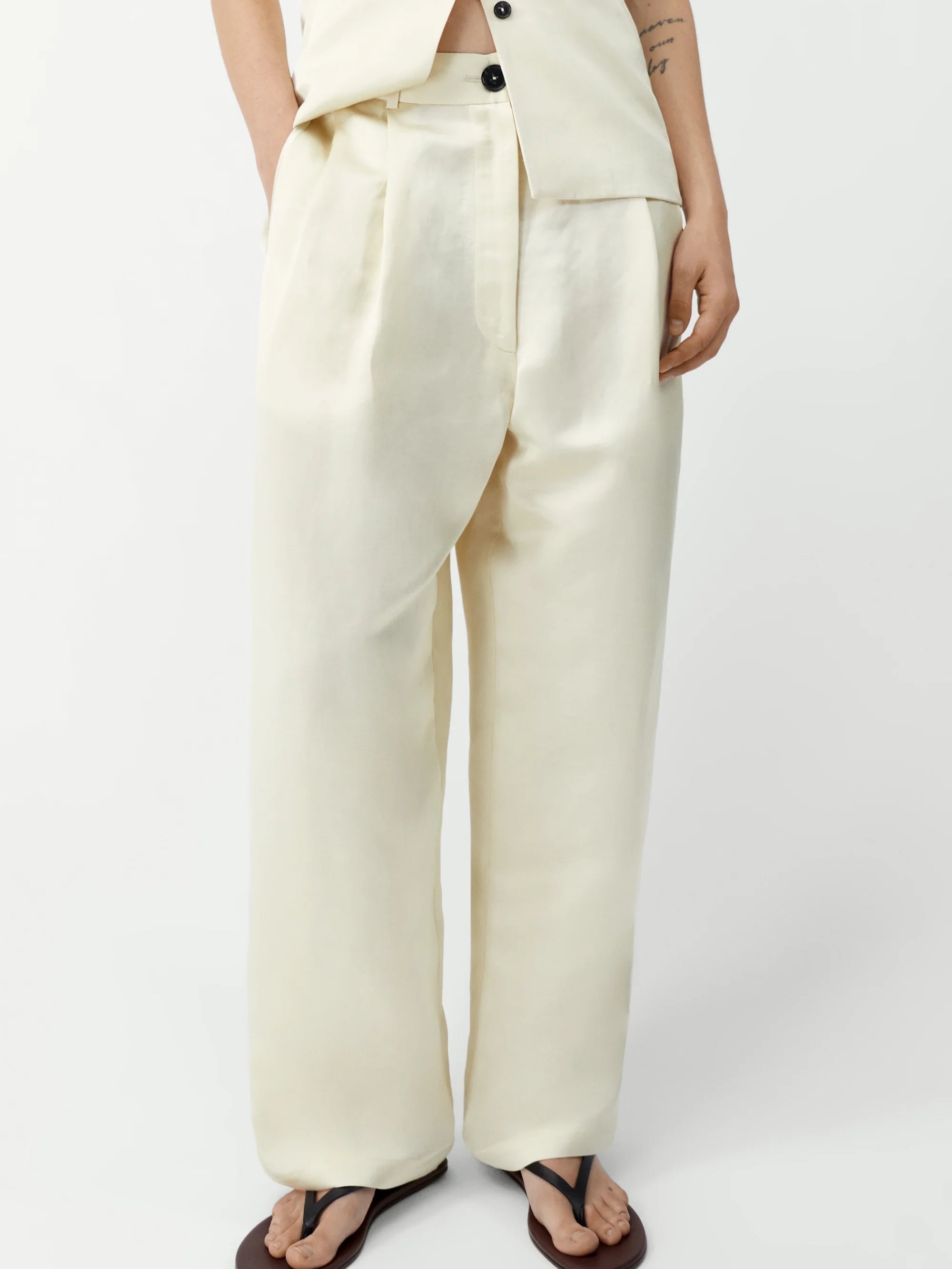 Person wearing a white outfit with wide-leg pants on a plain background