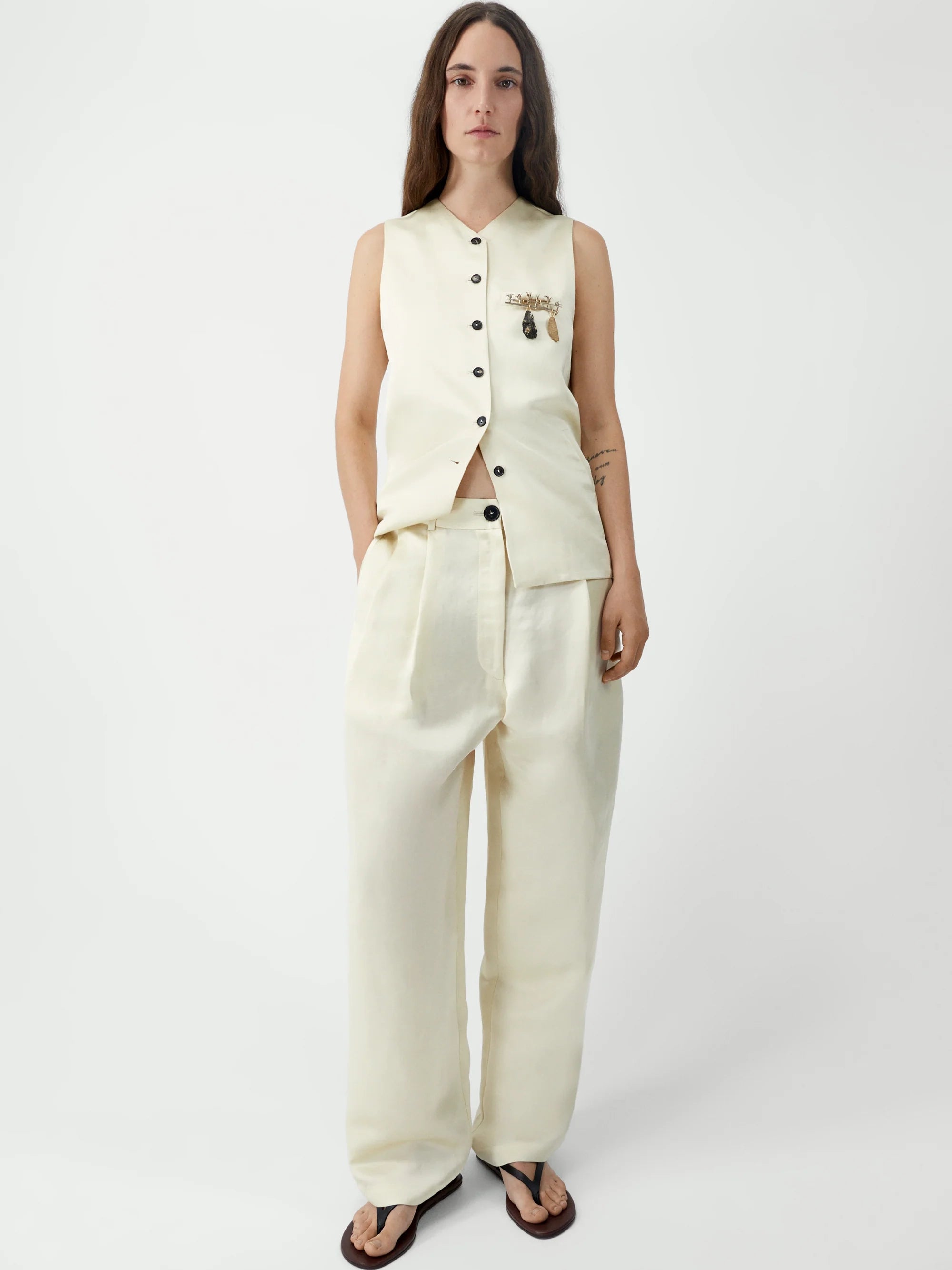 Woman wearing a cream-colored suit with a vest and pants on a white background