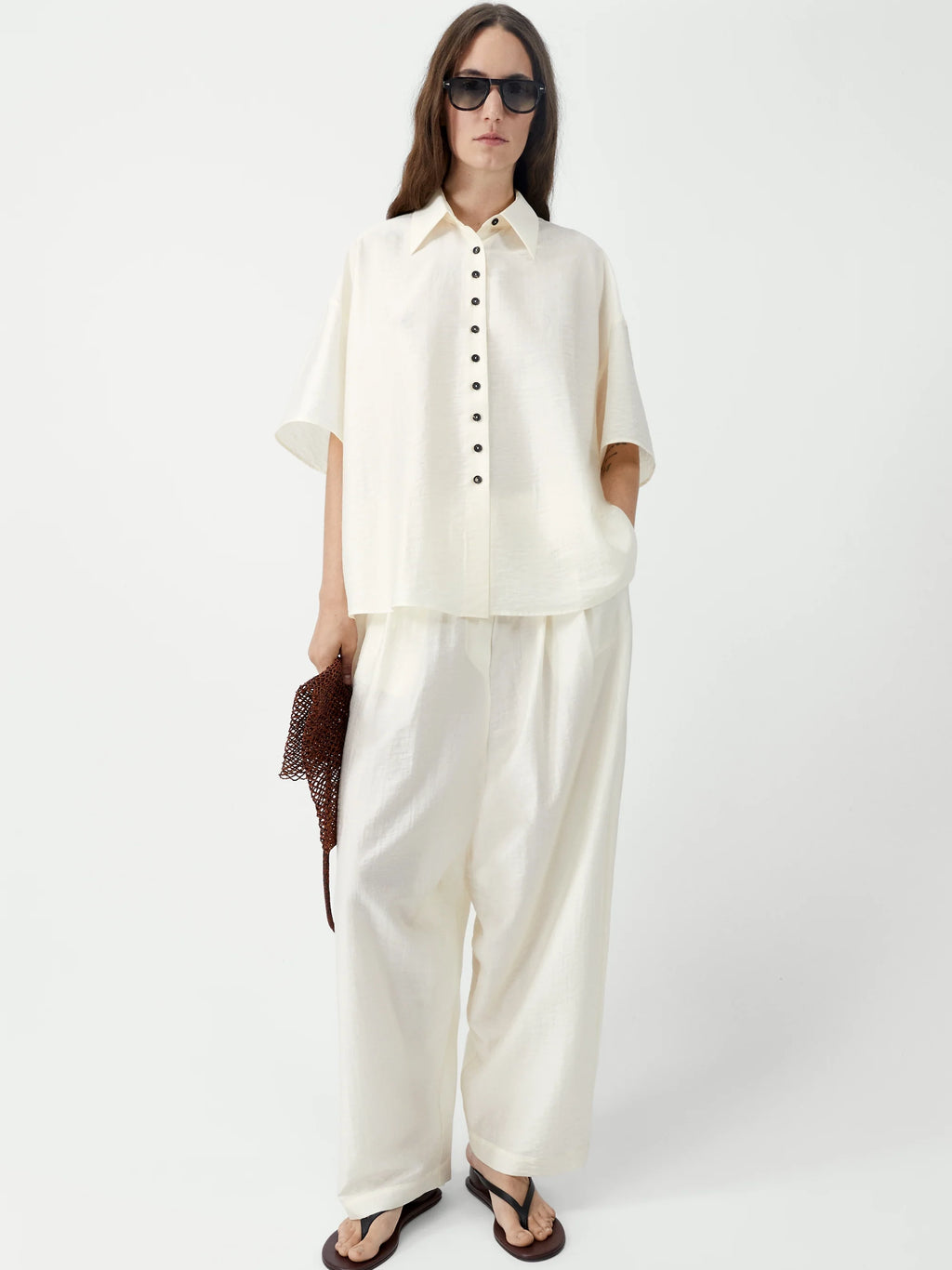 Woman wearing a white outfit with sunglasses on a white background