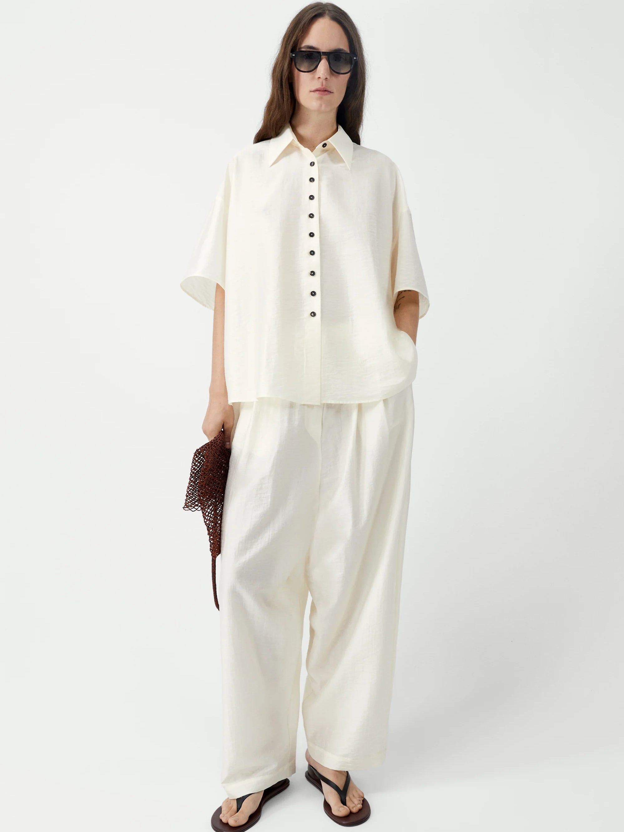 Woman wearing a white outfit with sunglasses on a white background