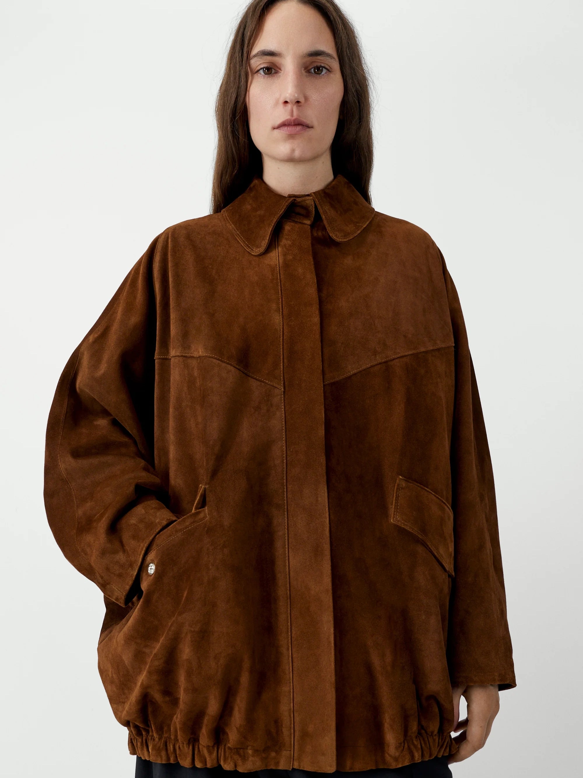 Person wearing a brown suede jacket on a white background