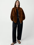 Person wearing a brown jacket and black pants on a white background