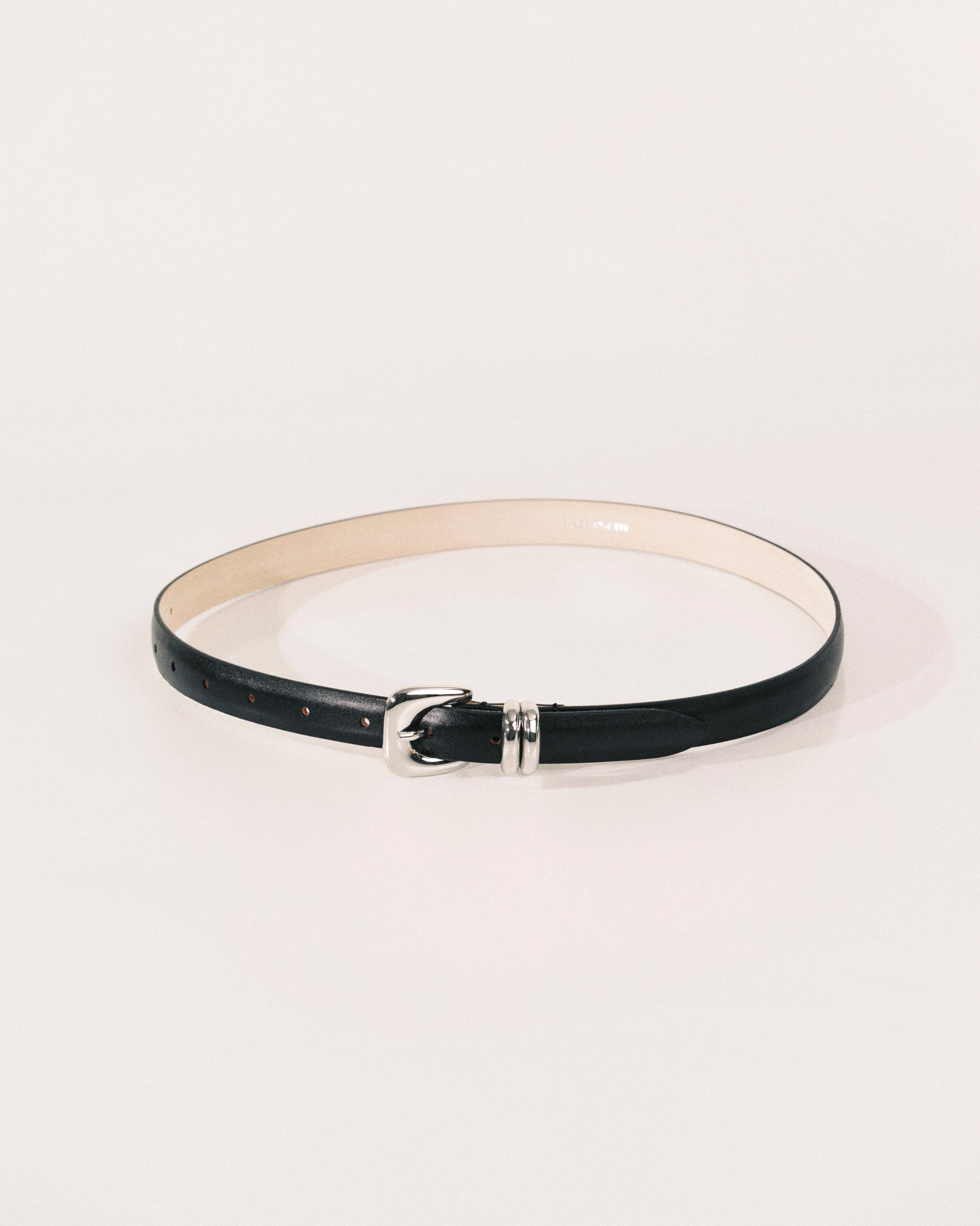 Black leather belt by Déhanche with sculptural silver-tone buckle and curved metal keeper.