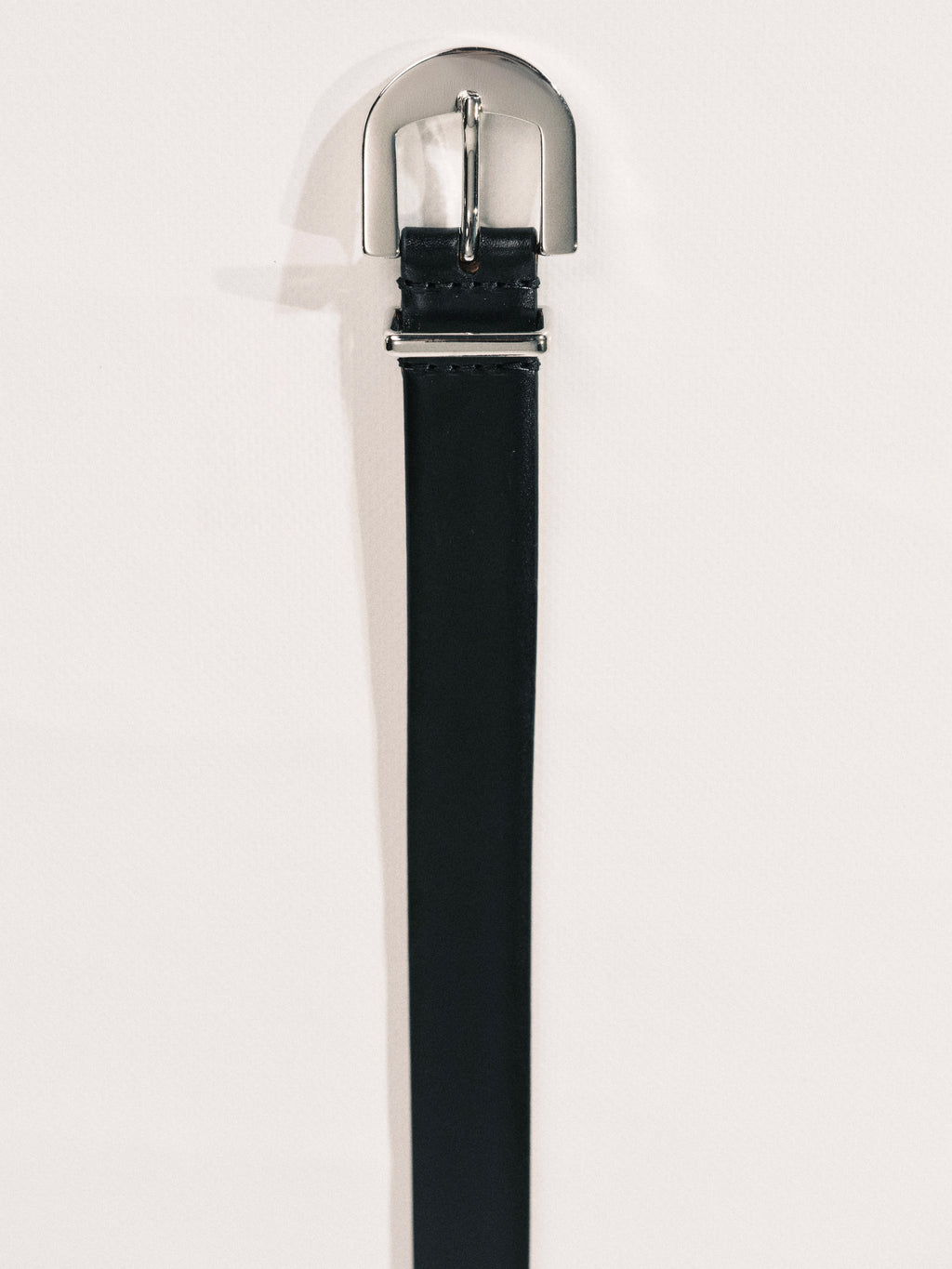 Black belt with silver buckle on a light gray background