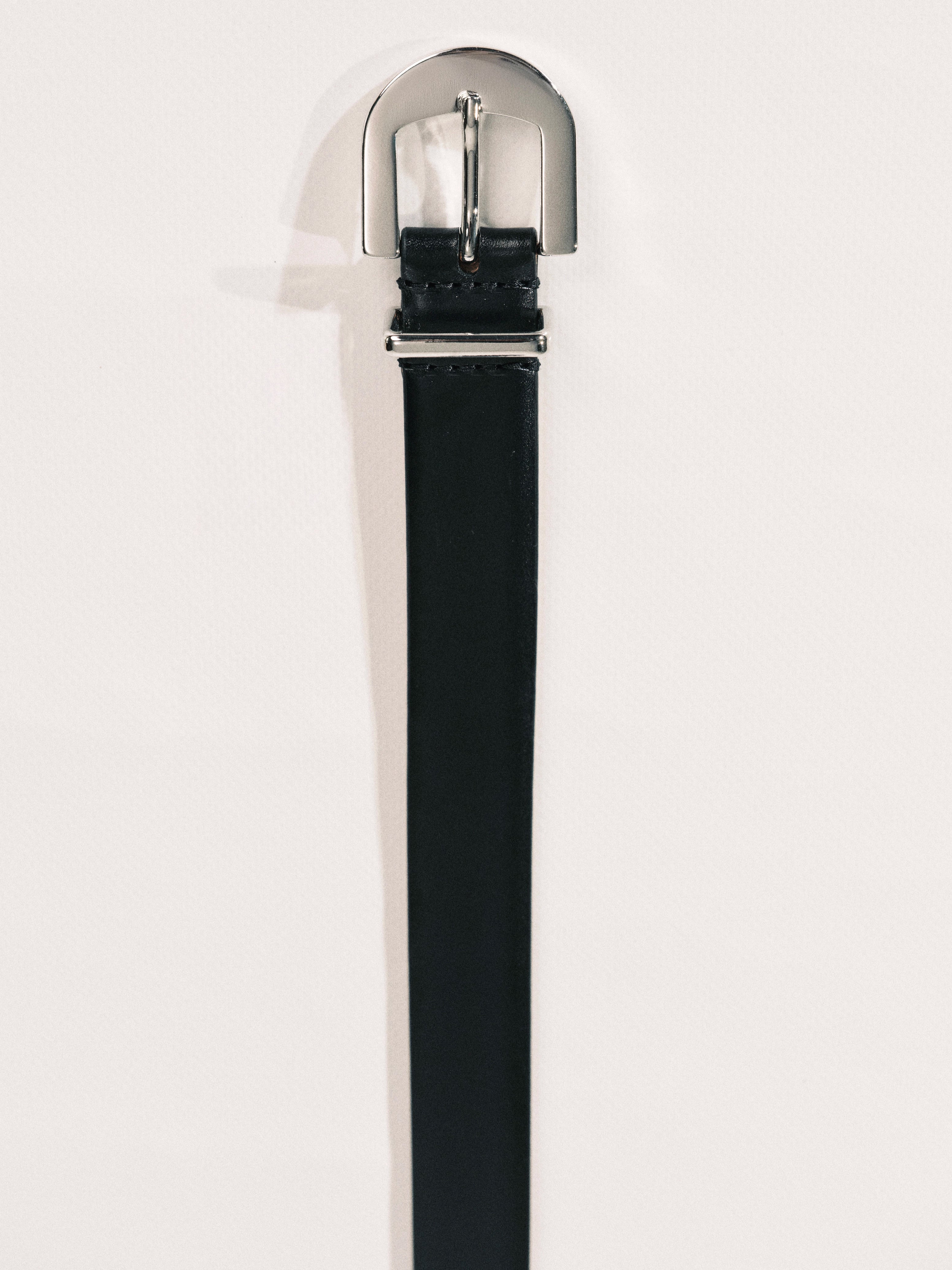 Black belt with silver buckle on a light gray background