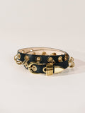 Black leather bracelet with gold chain and clasp on a light gray background