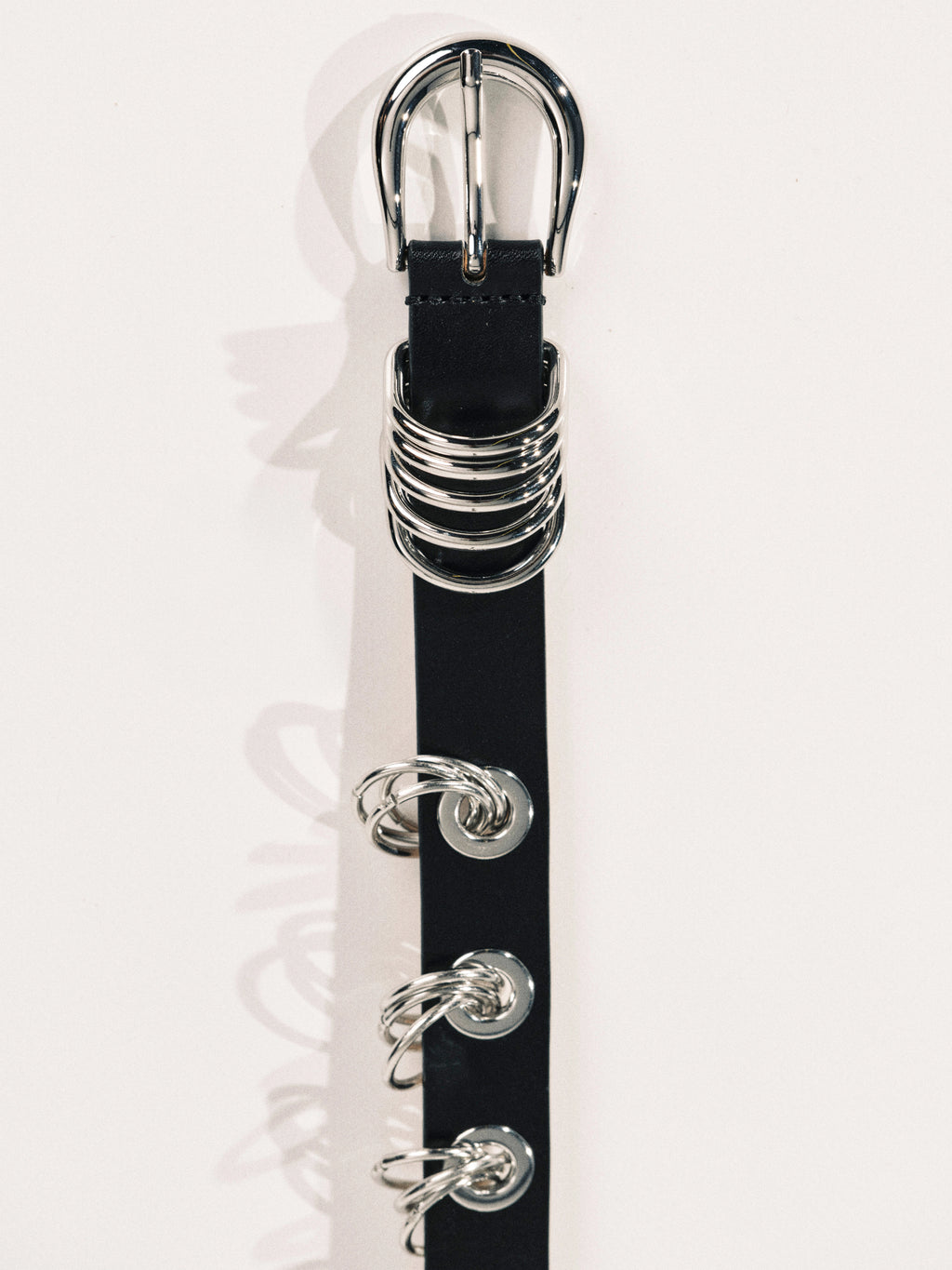 Black belt with silver buckle and decorative rings on a white background