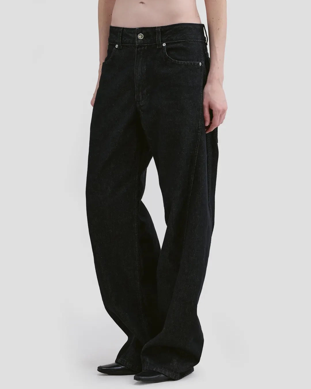 Detail view of model wearing Eckhaus Latta Bend Jean in black rinse with a loose bowed leg and twisted side seams.
