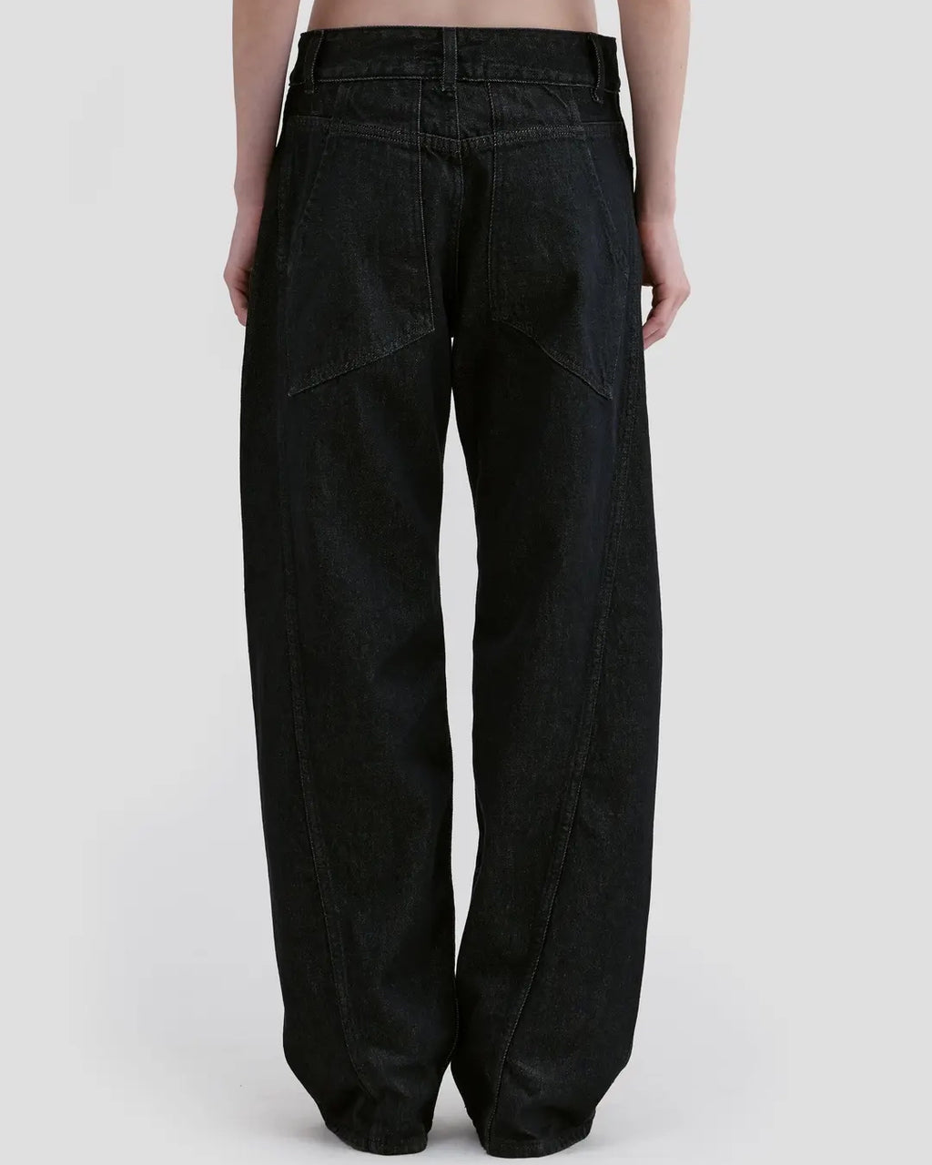 Back detail view of model wearing Eckhaus Latta Bend Jean in black rinse with a loose bowed leg and twisted side seams.