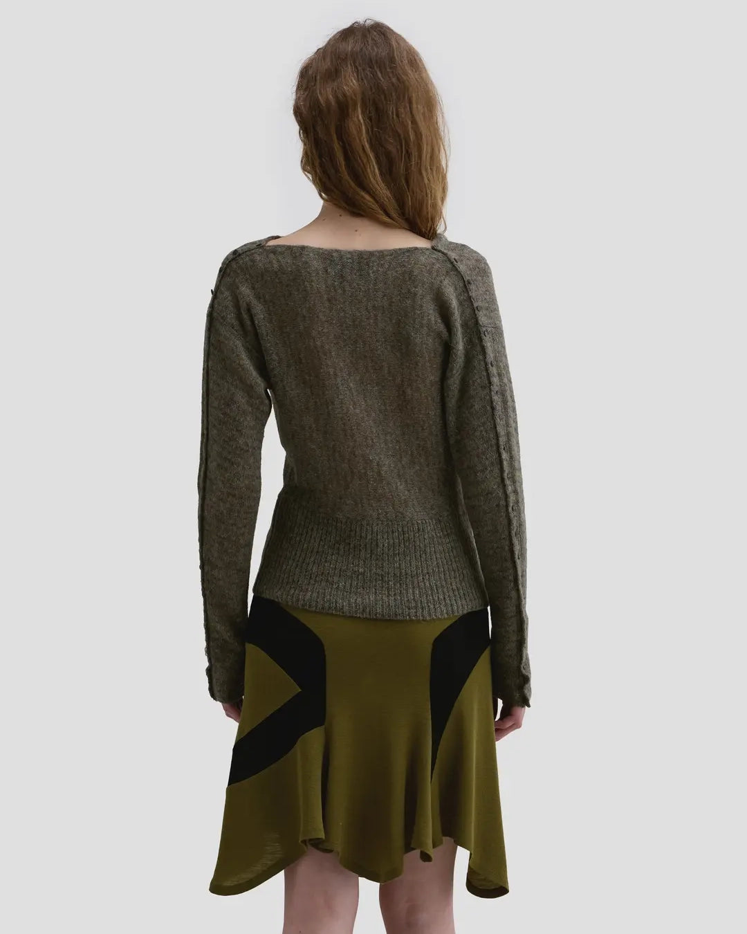 Back view of model wearing the Eckhaus Latta Grid Sweater in fern with a cowl neckline and buttoned sleeves.