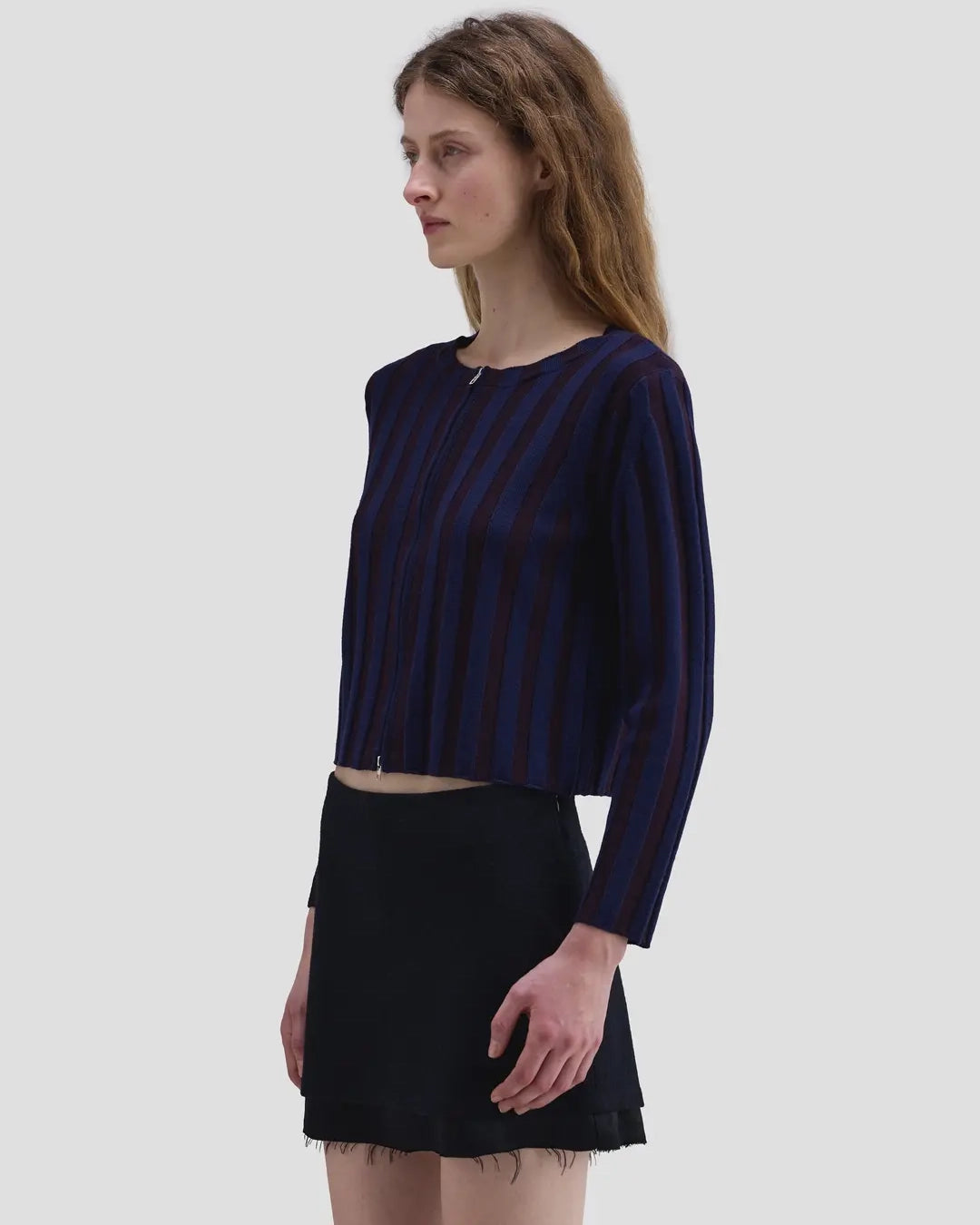 Side view of model wearing the Eckhaus Latta Keyboard Zip Cardigan in port with a fitted shape, contrast stripes and front zip.